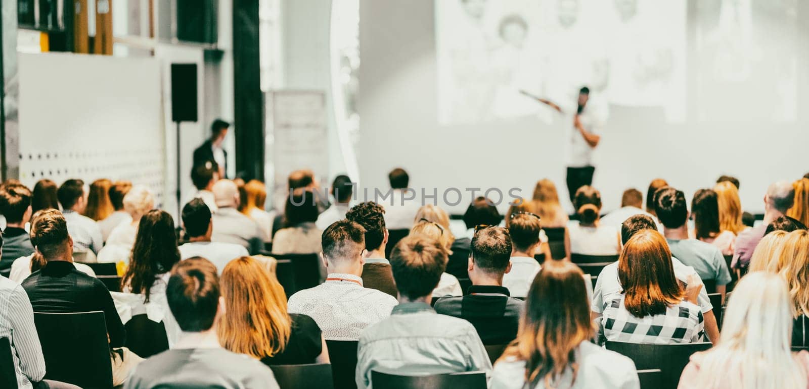 Speaker giving a talk in conference hall at business event. Rear view of unrecognizable people in audience at the conference hall. Business and entrepreneurship concept.
