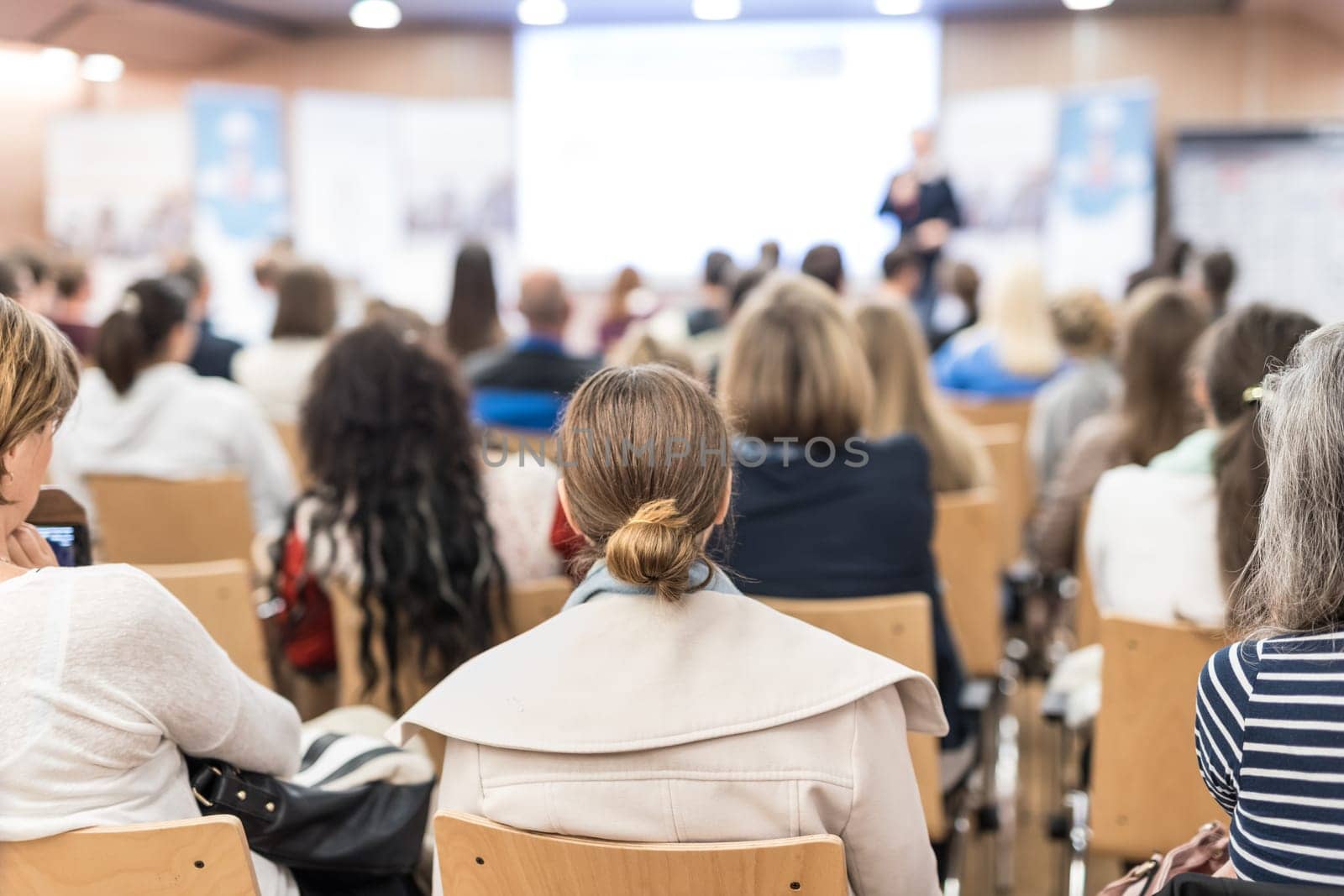 Speaker giving a talk in conference hall at business event. Audience at the conference hall. Business and Entrepreneurship concept. Focus on unrecognizable people in audience.