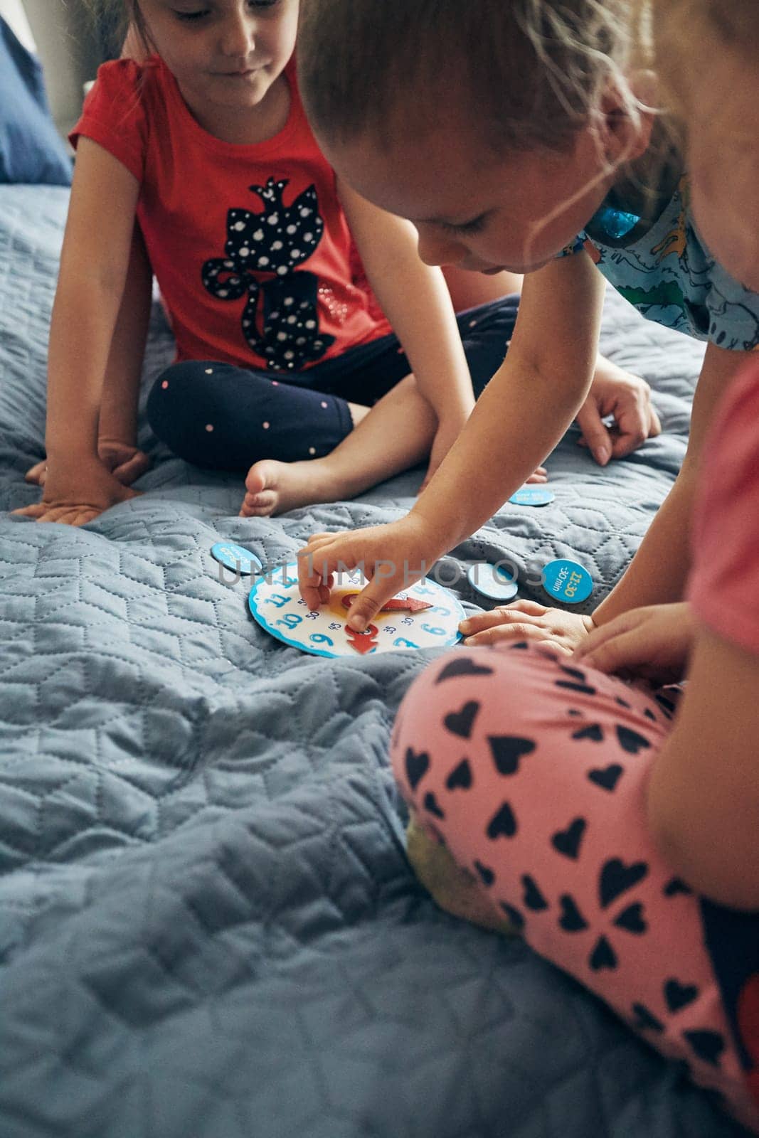 Kids learning how to tell time from clock and set the hands in the correct position. Teaching preschoolers tell time. Candid people, real moments, authentic situations