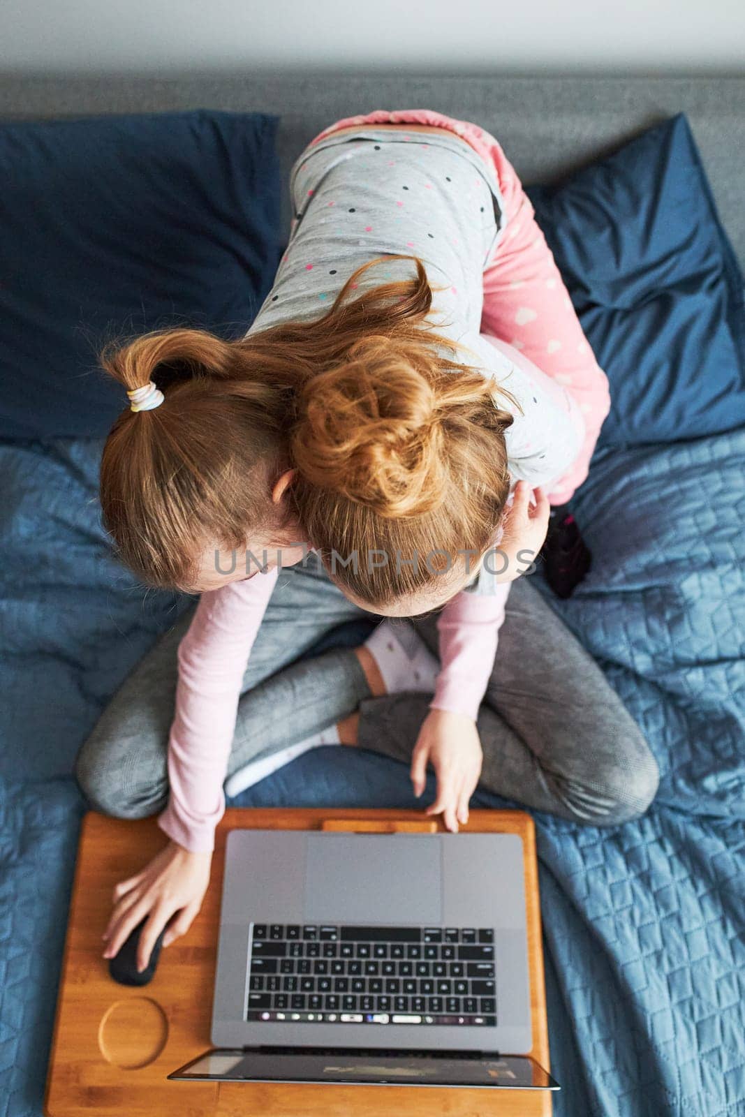 Grandchildren teenage girl and her younger sister talking on video call with granparents on laptop from home during COVID-19 quarantine. Girls sitting on bed in front of computer