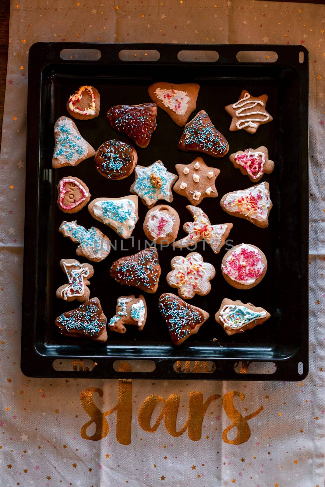 Christmas gingerbread cookies in many shapes decorated with colorful frosting, sprinkle, icing, chocolate coating, toppers, put on tray