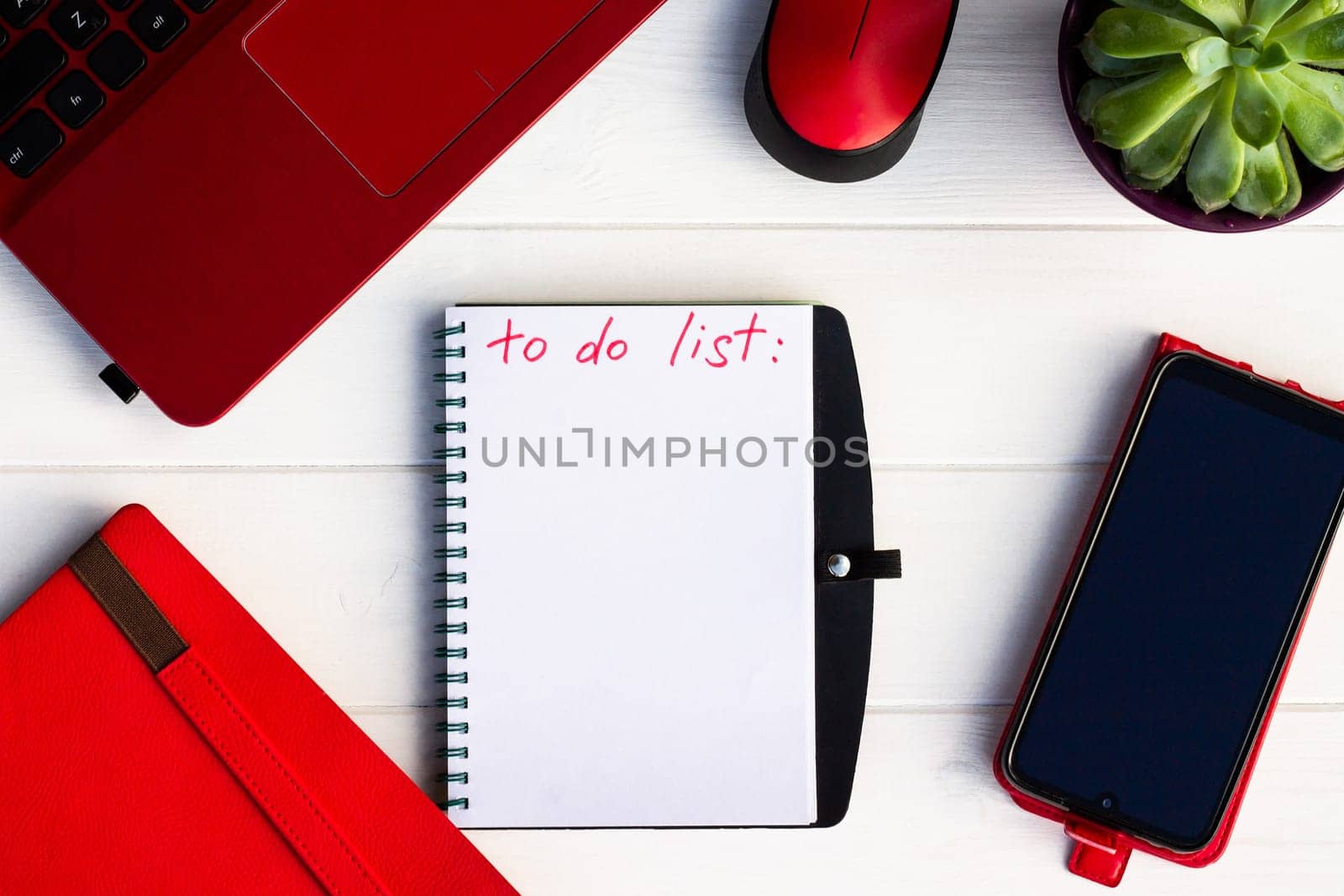 Notebook with To Do List with phone, red diary and laptop on a white wooden background. Top view. Copy space