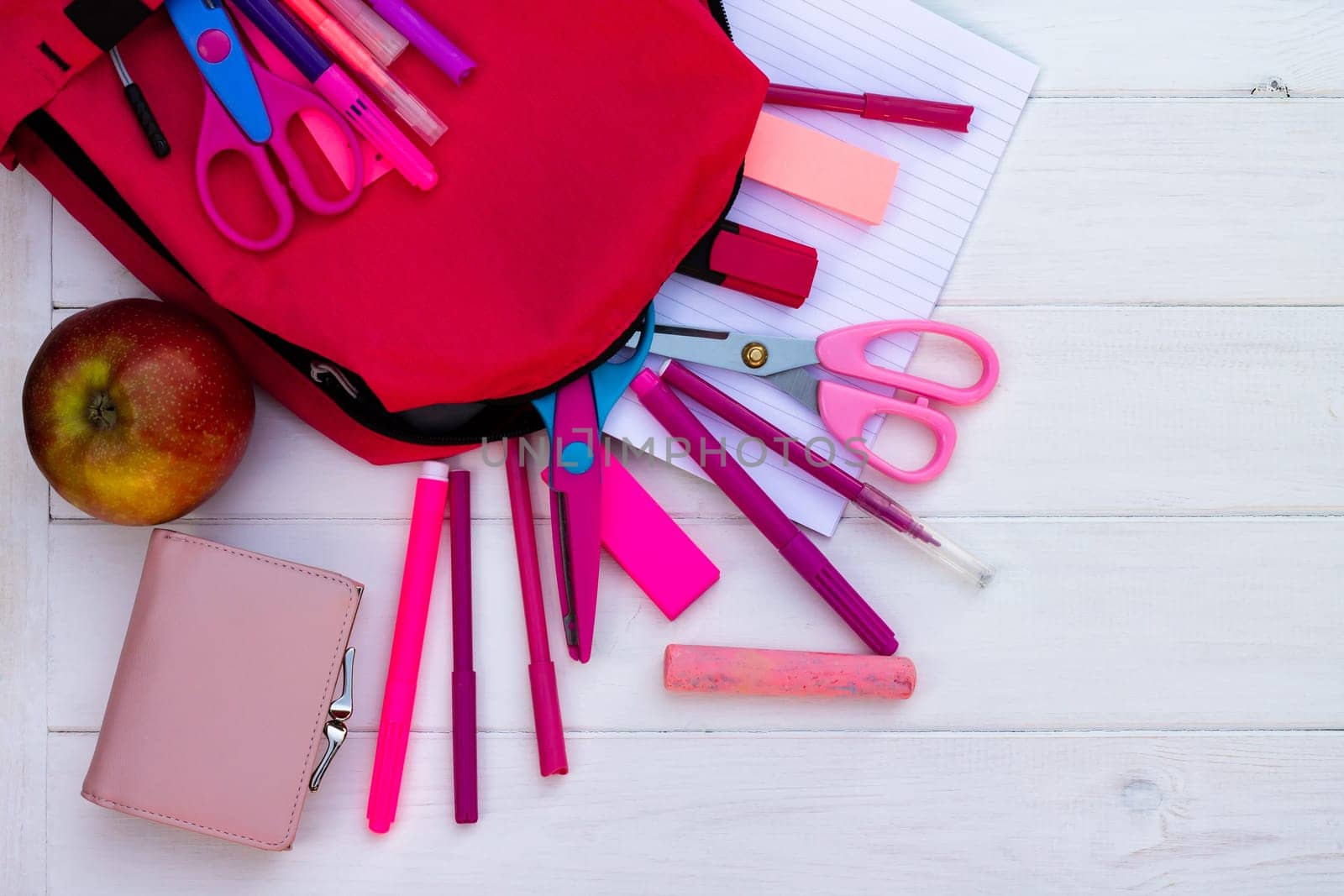 Pink school supplies, backpack on a white wooden background. Top view. Copy space. Education and back to school concept.