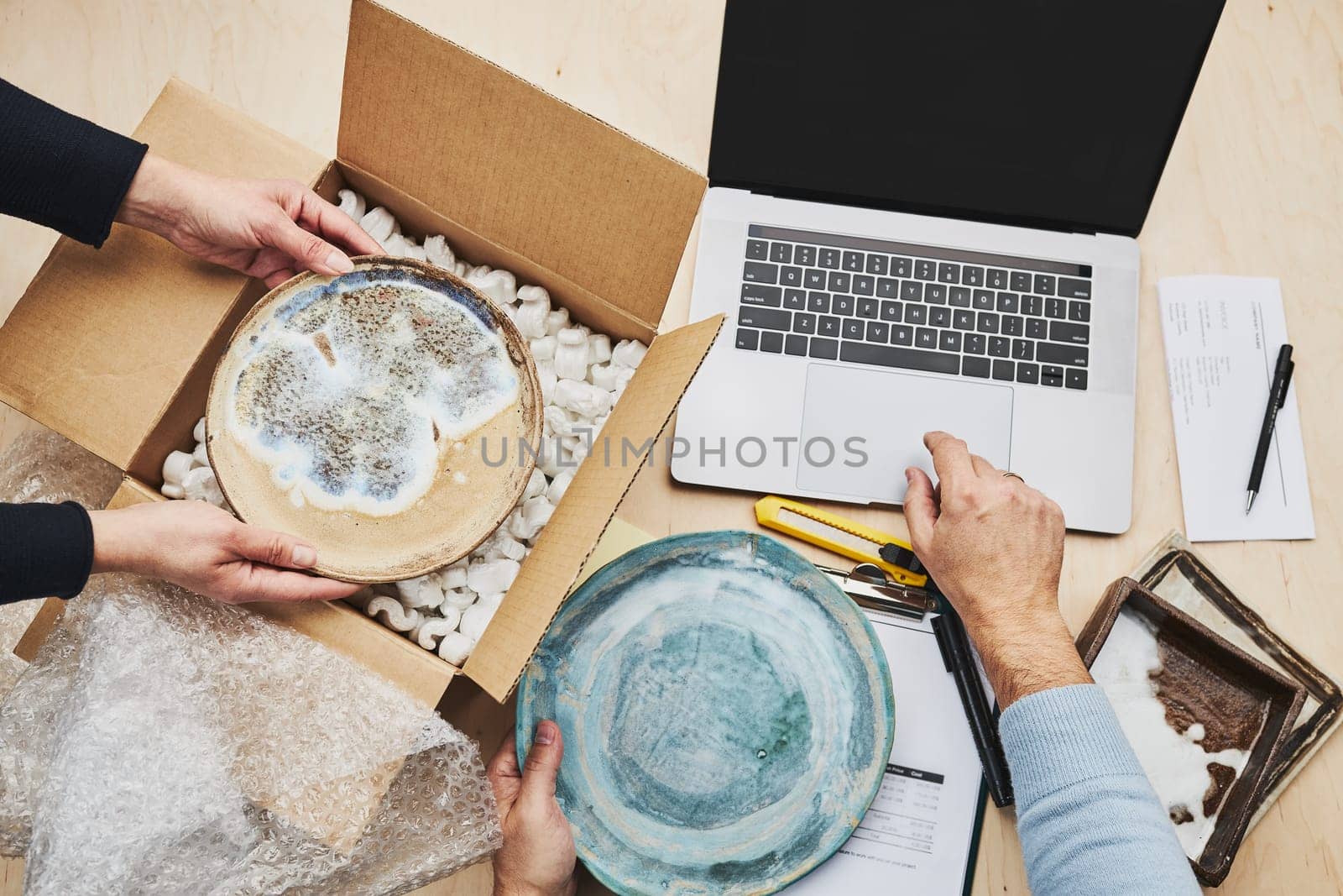 Business owner packing online order to delivery to customer. Preparing parcel box with ceramic plate product from online shop