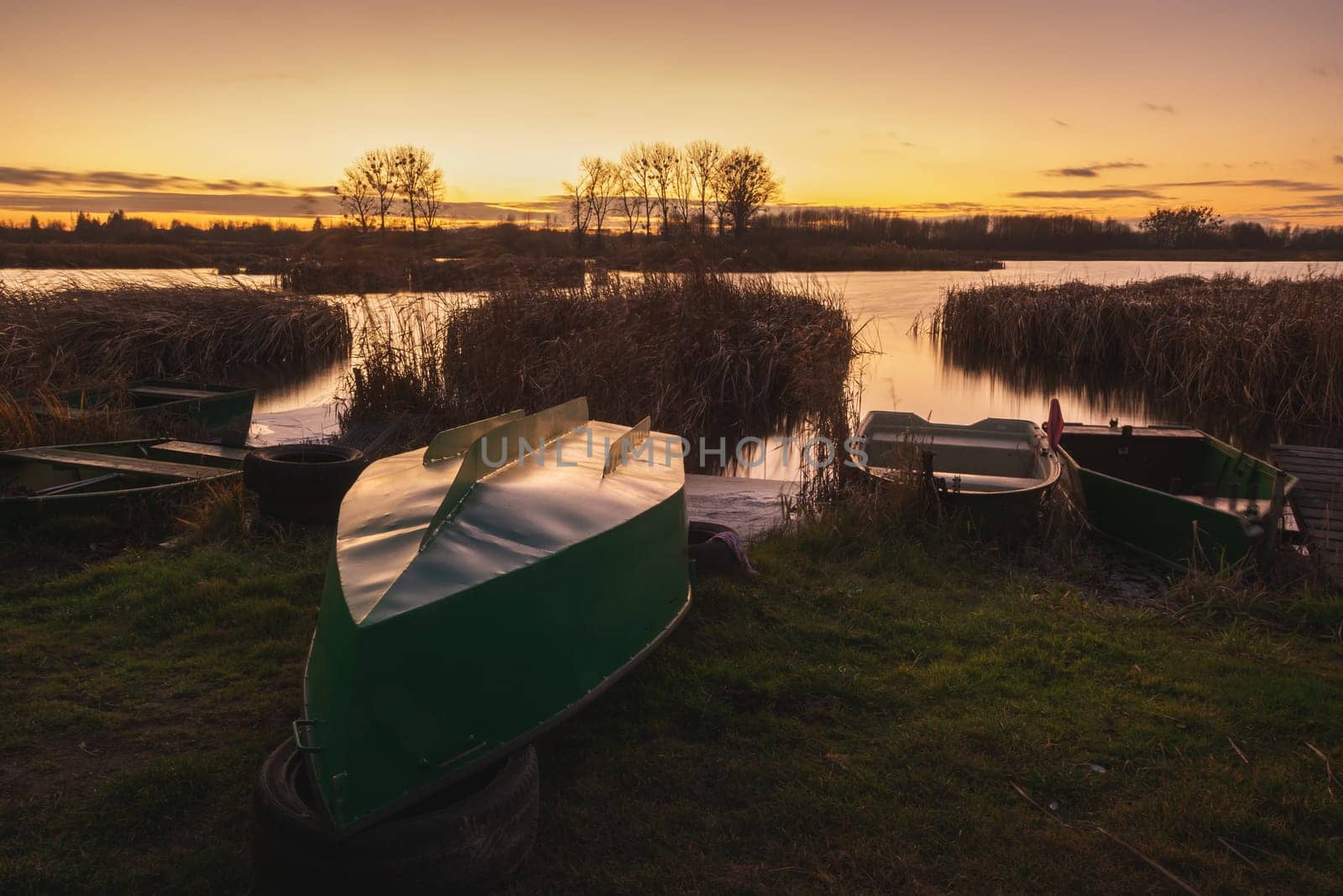 Anglers' boats on the lake shore and evening sky, autumn landscape
