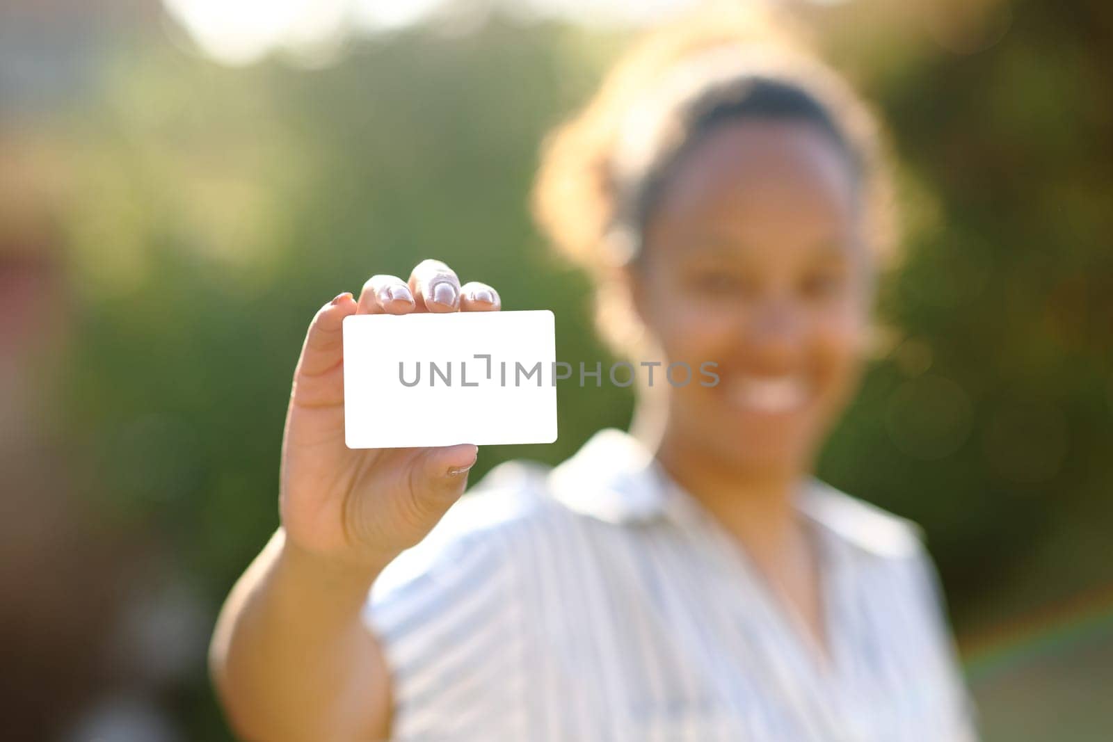 Black woman showing credit card mock up in a park
