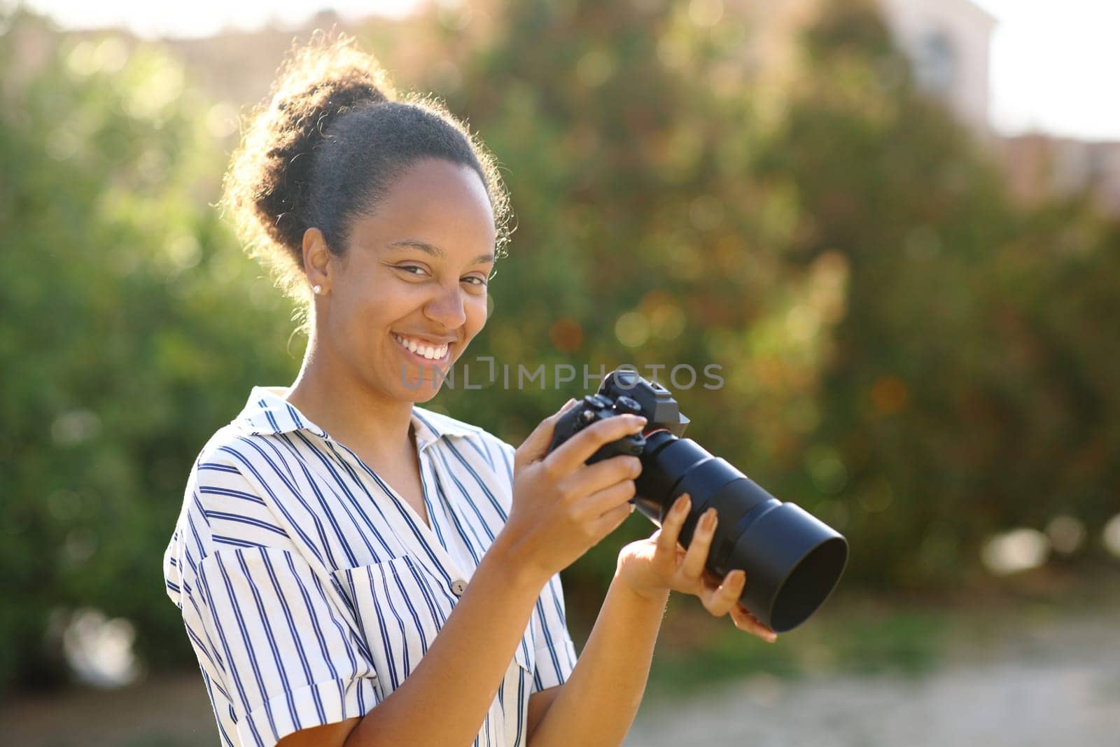 Happy black photographer posing looking at camera in a park