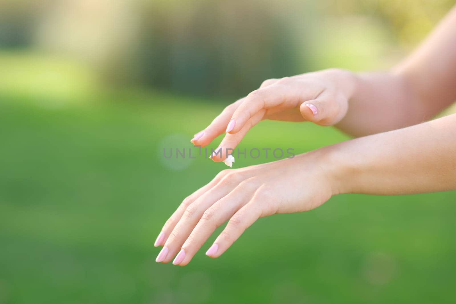 Close up of a woman hands hydrating skin with cream in a park