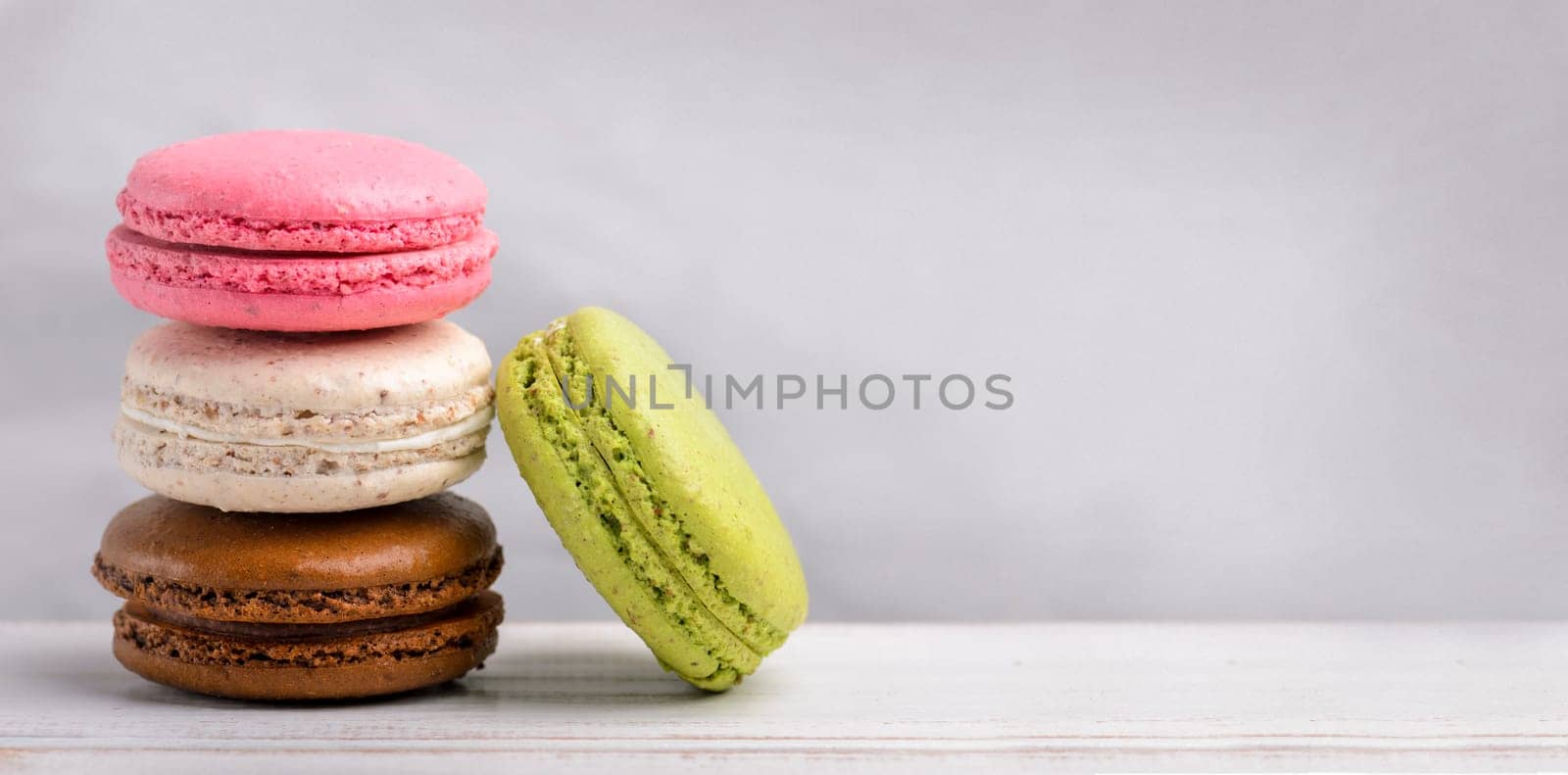 Retro pastel colorful macaroon cookies on vintage background with copyspace. Homemade french macaron dessert with different flavors: chocolate, strawberry, vanilla, pistachio. Candy shop sweet menu design.