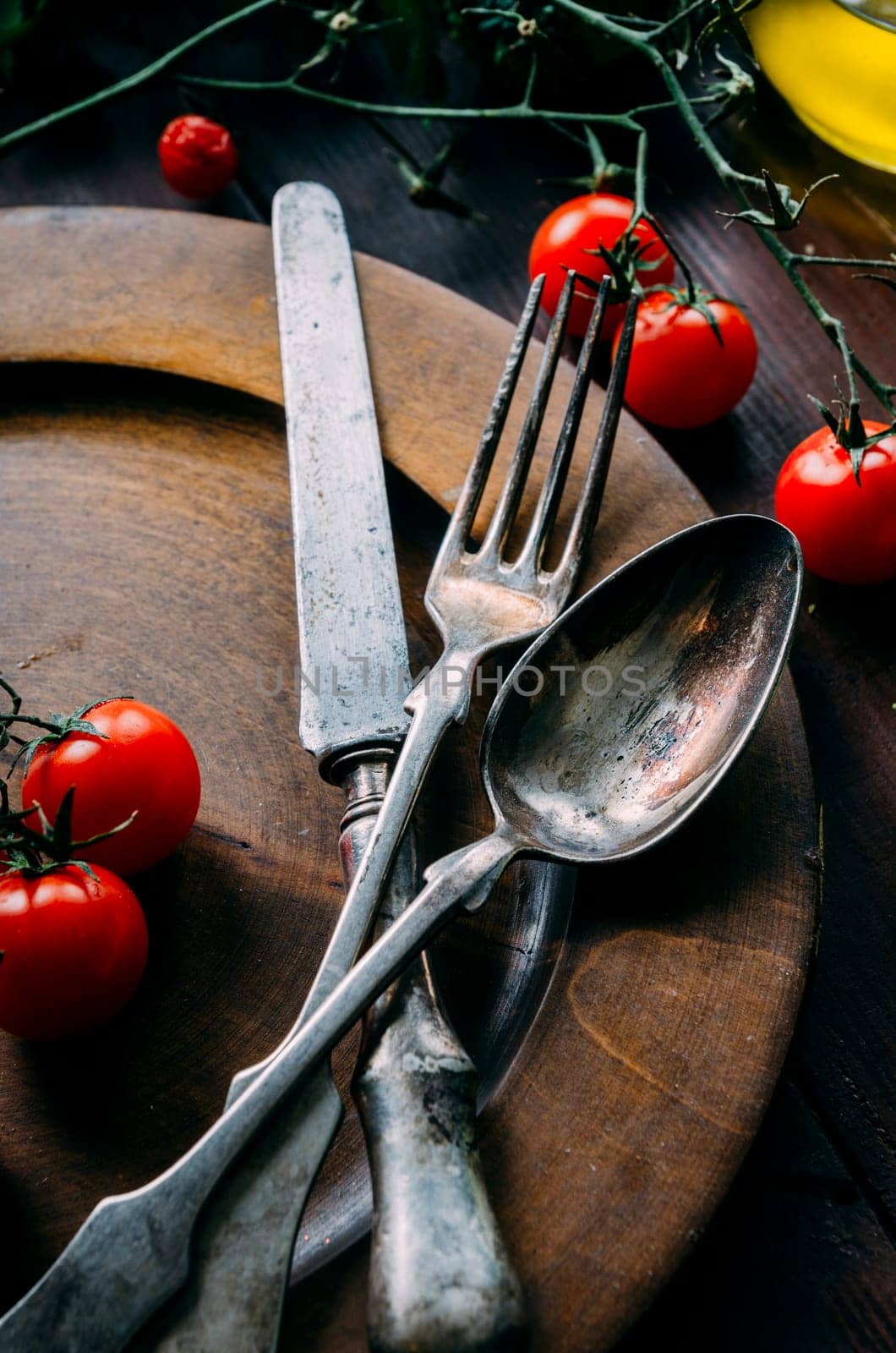 Vintage table setting with old silver spoon, fork and knife in dark wooden plate from above. Creative thanksgiving dinner still life. Restaurant silverware set top view.