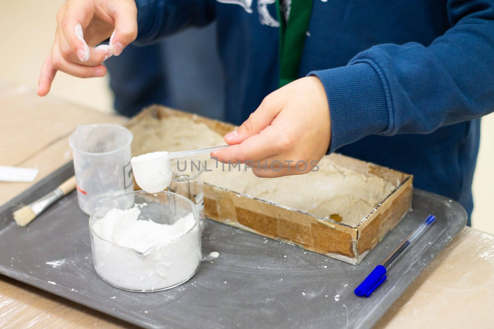 Child's hands are preparing a plaster mix in the laboratory for research