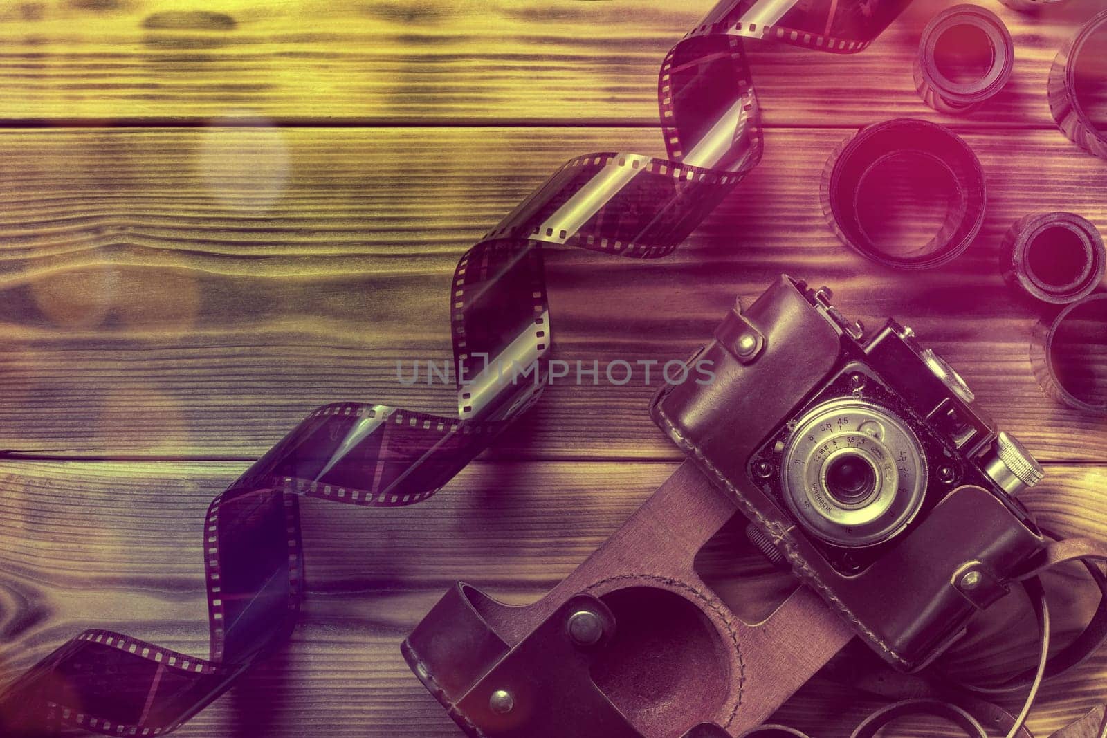 Retro photo camera with film on wooden table. Flat lay, copy space