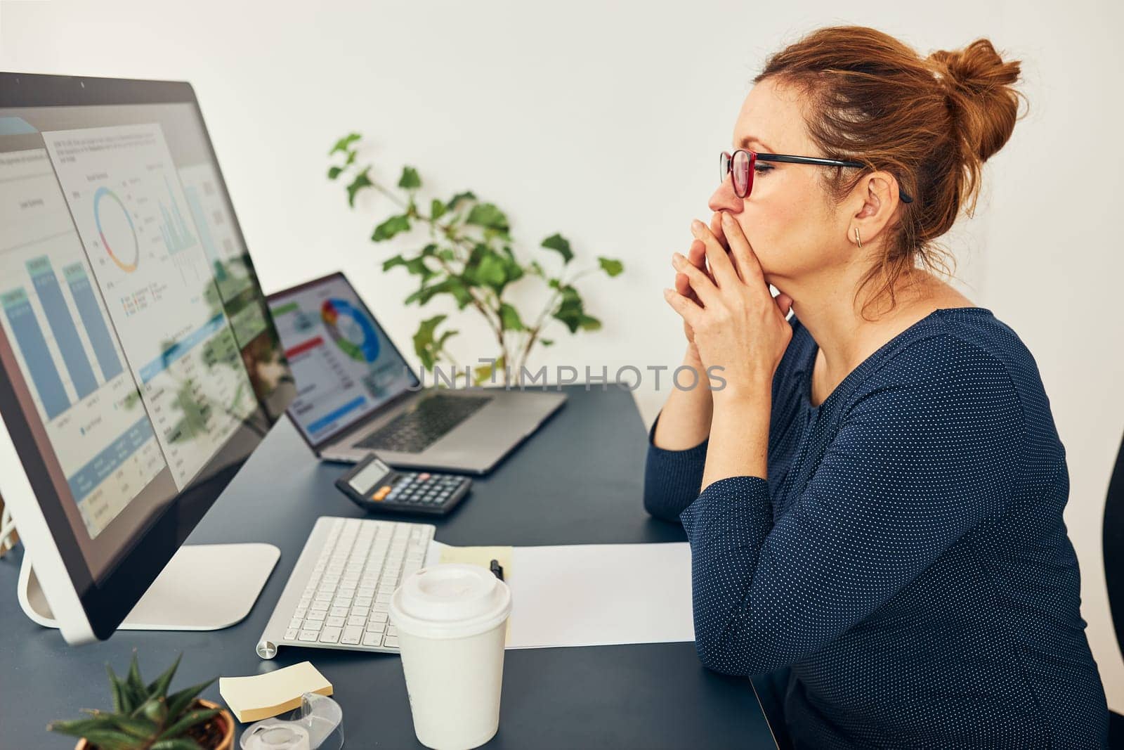 Woman entrepreneur focused on solving difficult work. Confused businesswoman thinking hard holding doccuments standing at her desk in office