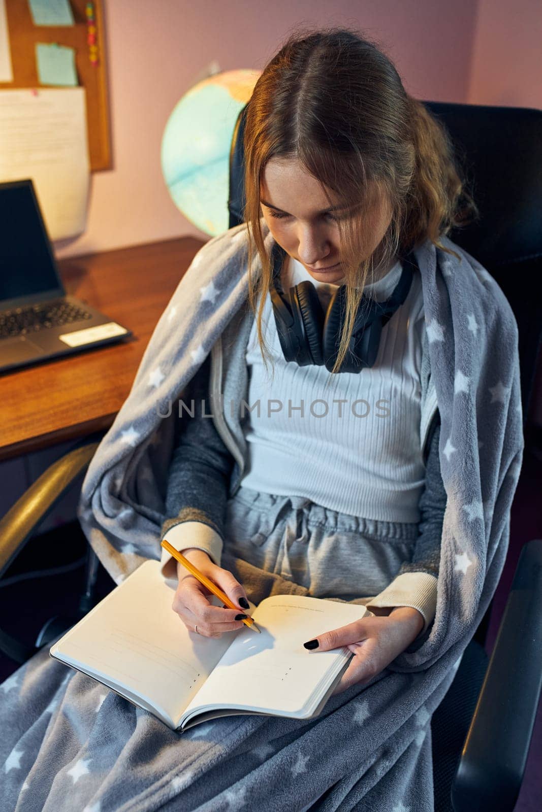 Student learning remotely from home. Young woman having classes online, making notes, reading and learning sitting at desk at home during quarantine