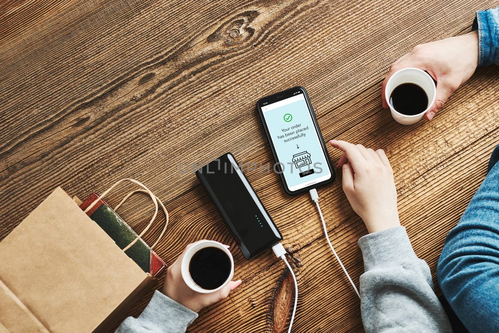 Online shopping. Paying online. Ordering product in online shop using smartphone. Payment confirmation on screen. Online banking. Paying for online shopping while charging mobile phone from powerbank in coffee shop