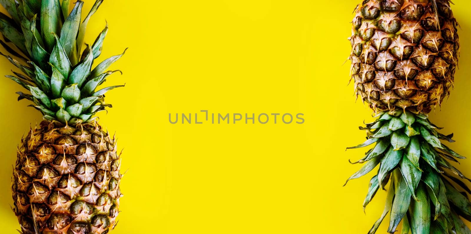 Top view of pineapple border on bright yellow background. Trendy summer smoothie tropical design. Flat lay. Vivid pastel layout with ananas frame from above. Creative food and drink menu.