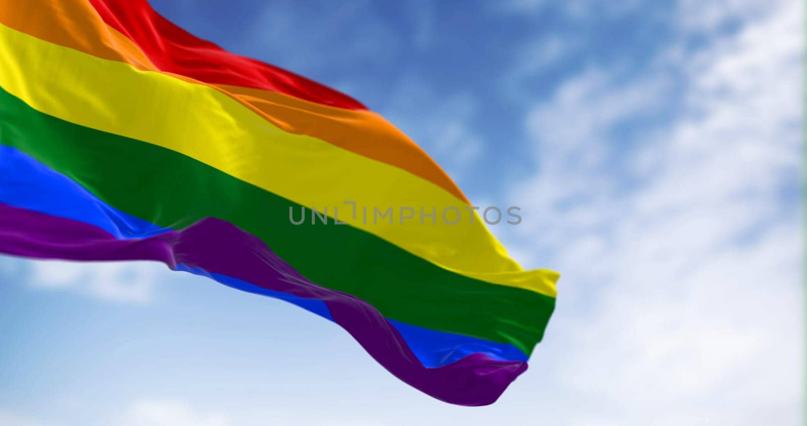 Rainbow flag waving on a clear day. Multicolored flag with stripes in the colors of the rainbow, often used as a symbol of LGBT pride. 3d illustration render. Selective focus. Fluttering fabric