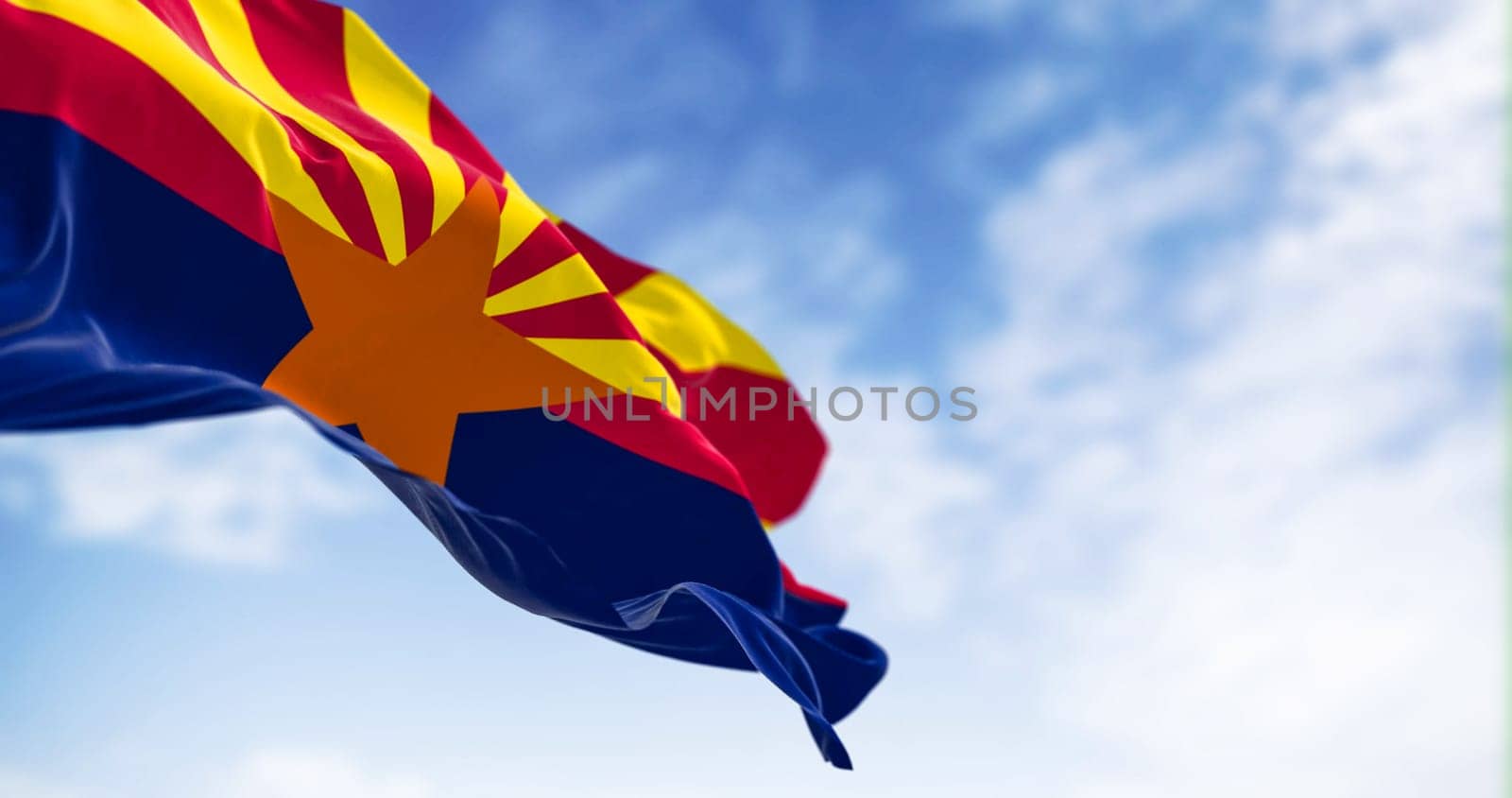 The flag of Arizona waving in the wind on a clear day. Copper star, 13 rays of red and yellow, and a blue bottom half. 3d illustration render. Selective focus. Fluttering textile