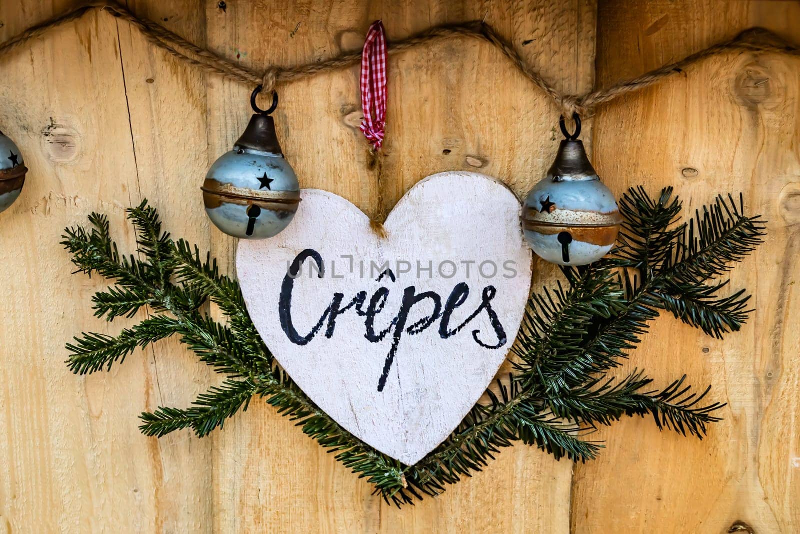 Sweet crepes - flat pancake - sign made of wood in the shape of a heart, hanging on bakery shop.