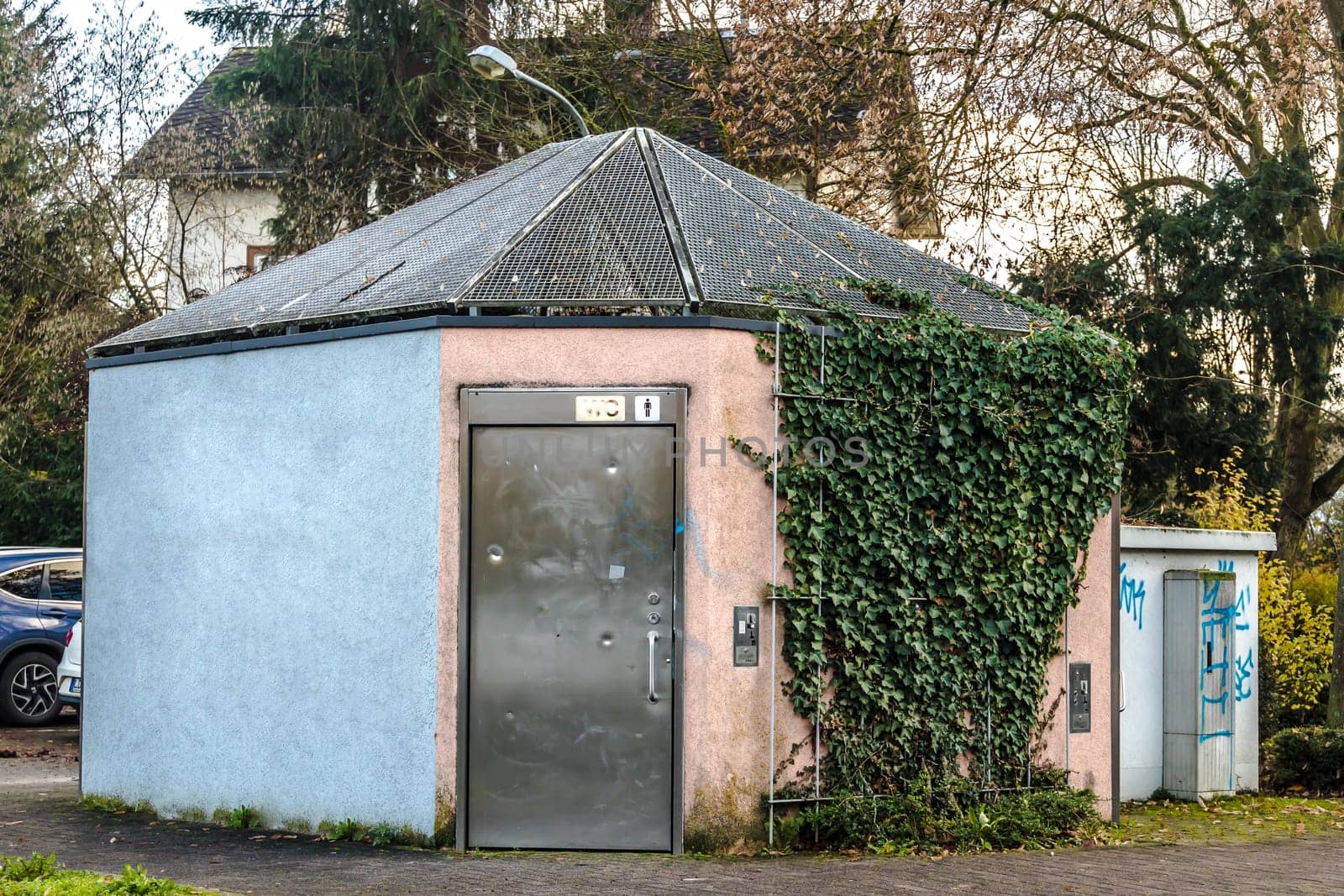 Public toilet in a city with graffiti and metal door