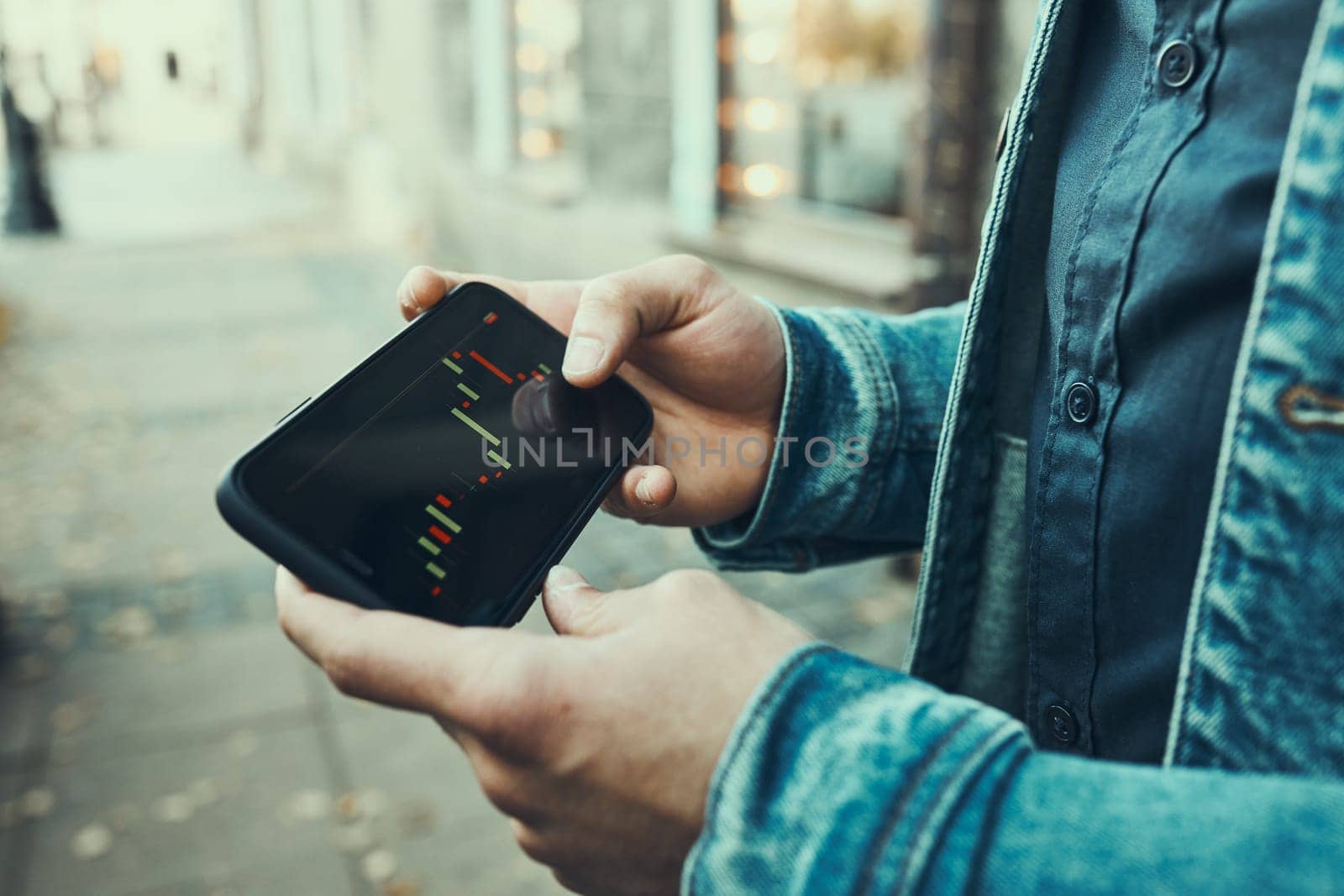 Person investing trading on stock cryptocurrency market using investing application on smartphone. Stock market investment in hand. Trader holding mobile phone looking at candle chart