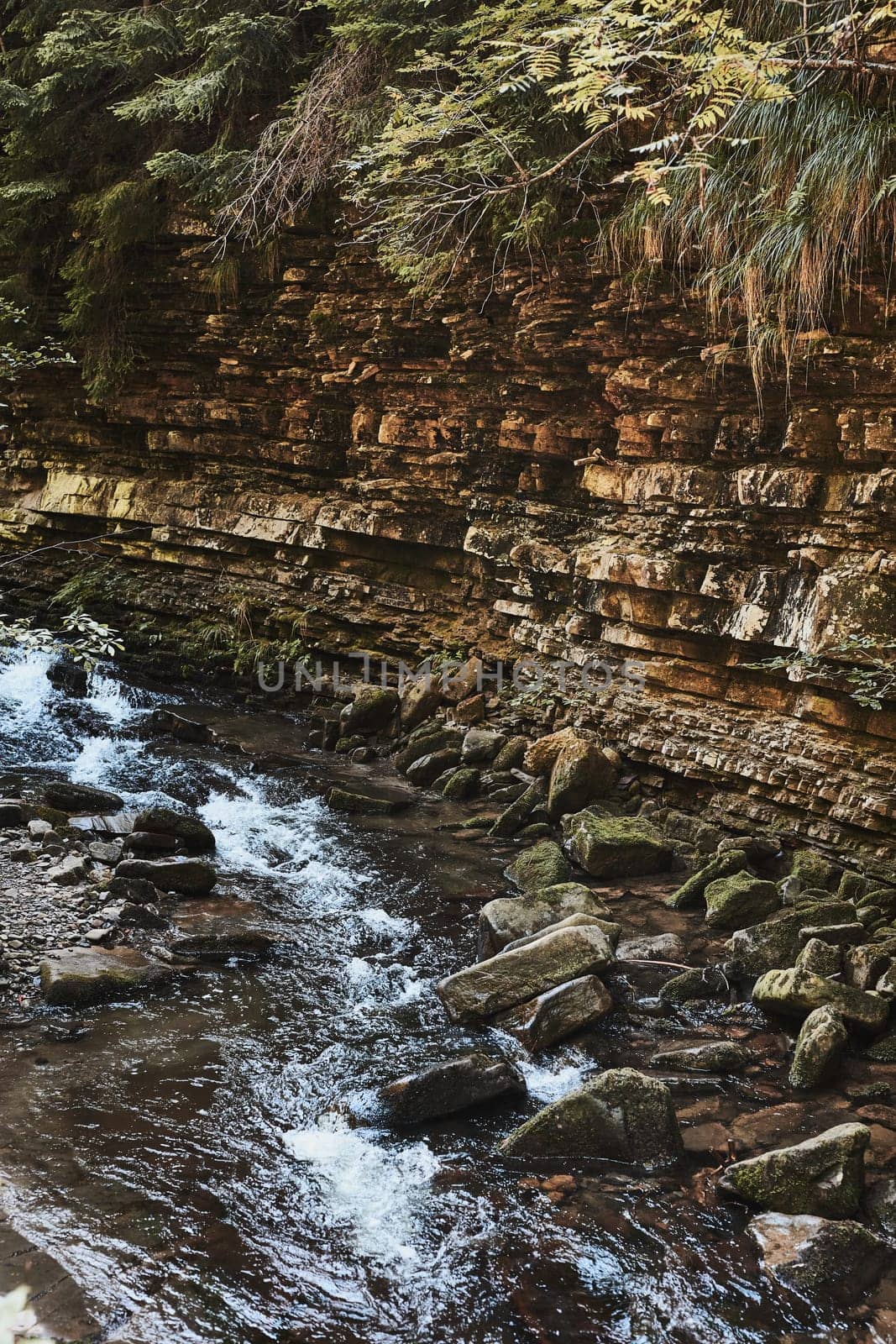 Mountain stream flowing down at rocky wall. Mountain landscape. Natural scene. Beauty in nature