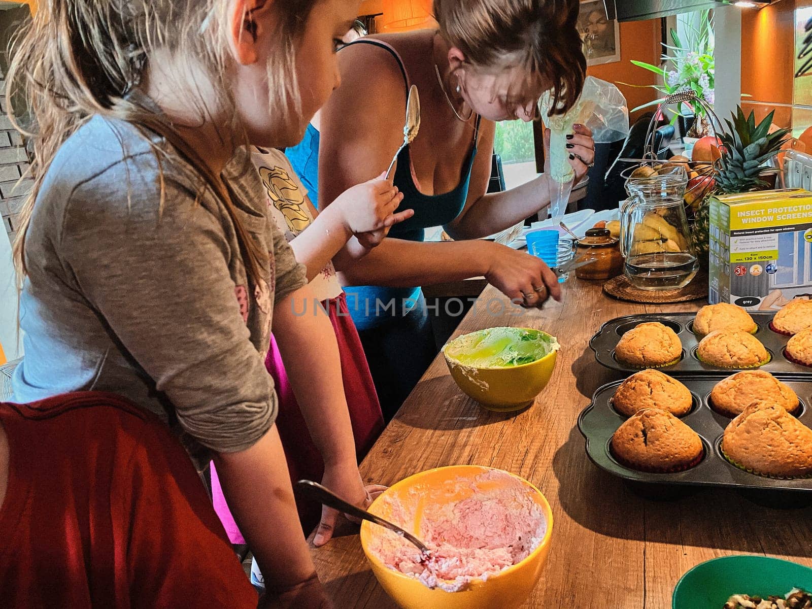 Group of children baking cupcakes, preparing ingredients, toppings, sprinkles for decorating cookies. Kids learning to cook, working together in kitchen at home. Concept of happy family