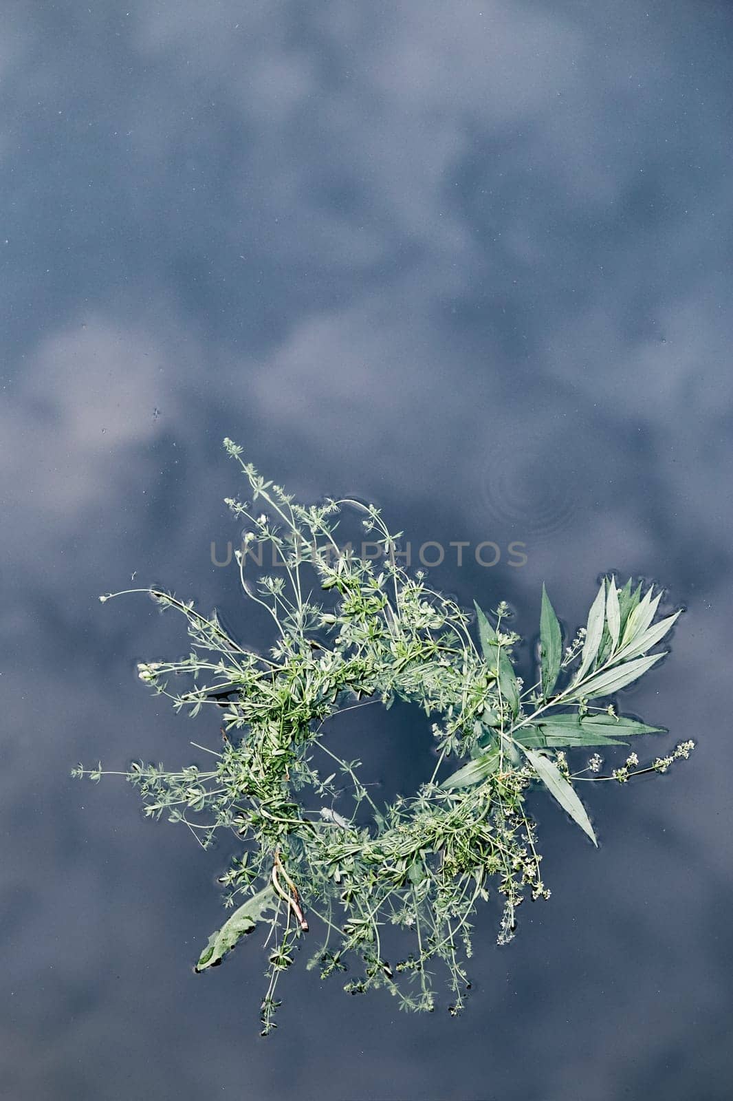 Wreaths of flowers and herbs floating on river. Midsummer divination