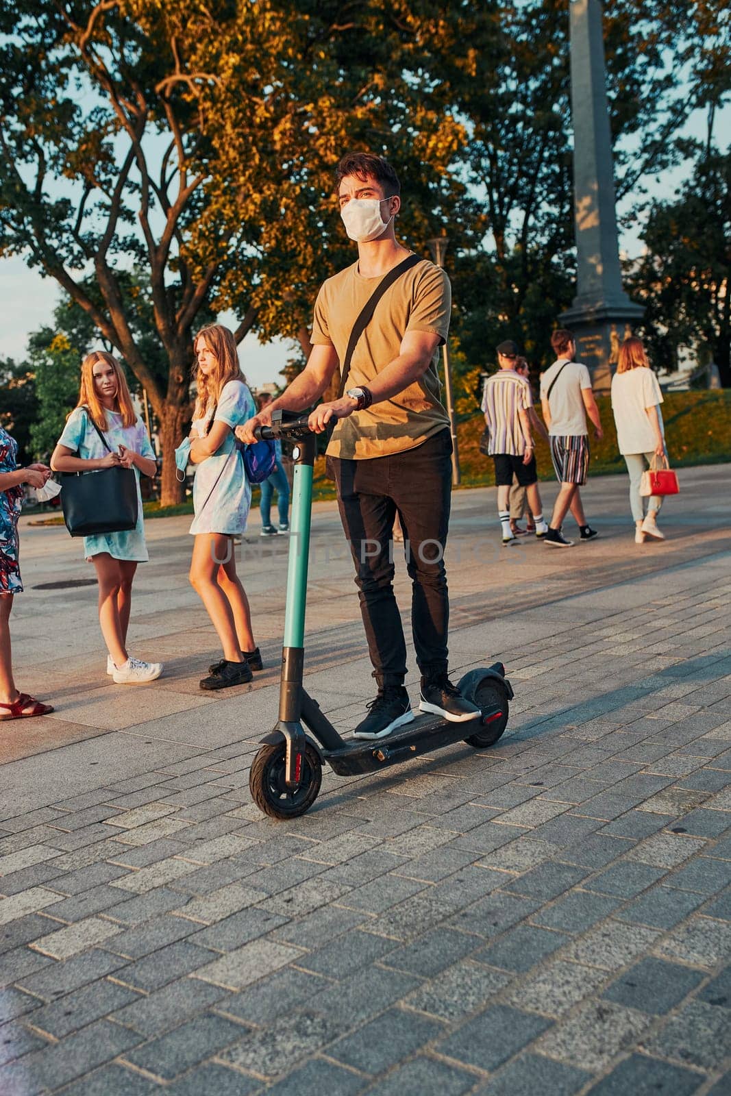 Young man riding an electric scooter in the city center. Man wearing the face mask to avoid virus infection and to prevent the spread of disease in time of coronavirus. Candid people, real moments, authentic situations