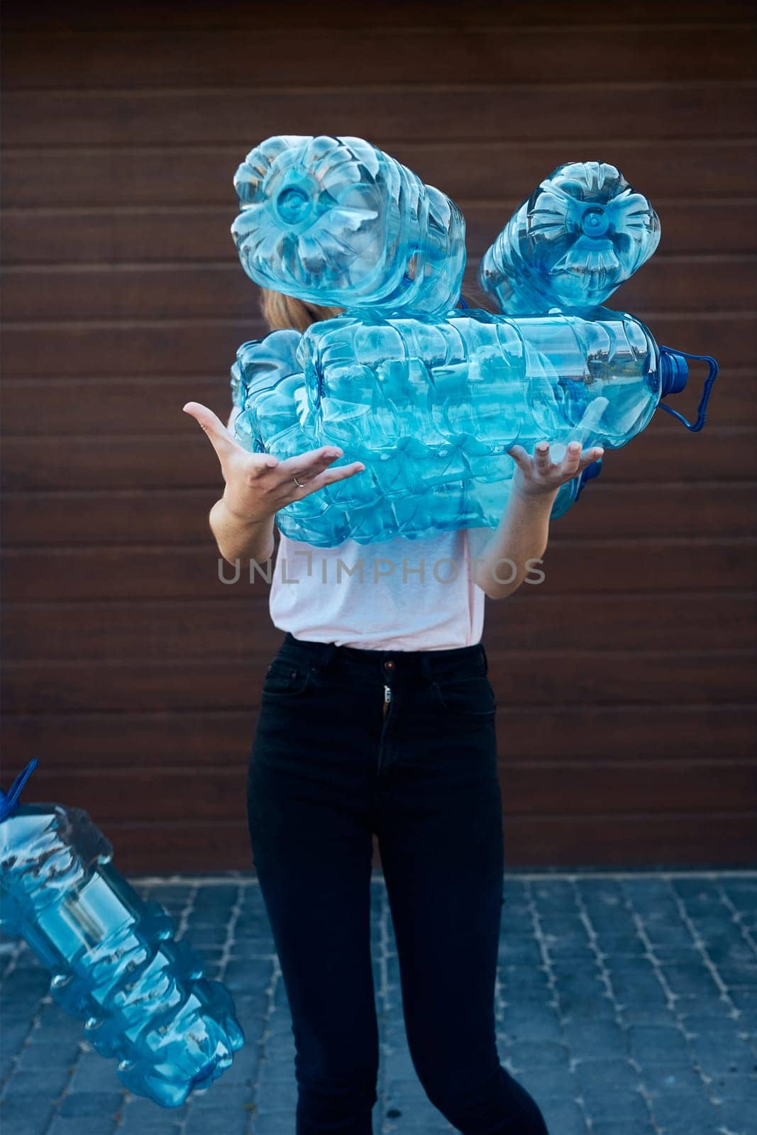 Young woman throwing out empty used plastic water bottles into trash bin. Collecting plastic waste to recycling. Concept of plastic pollution and too many plastic waste. Environmental issue