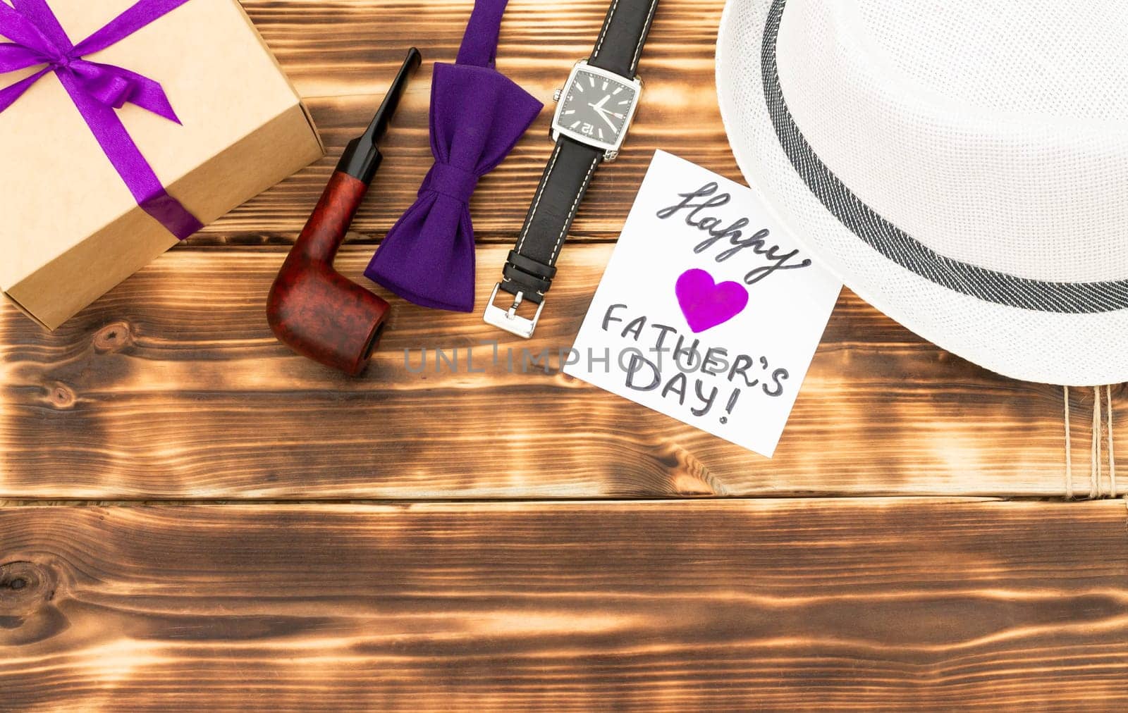 Greeting card Happy Father's Day with a gift box and men's accessories on a rustic wooden tabletop. Flat lay. Top view. Copy space
