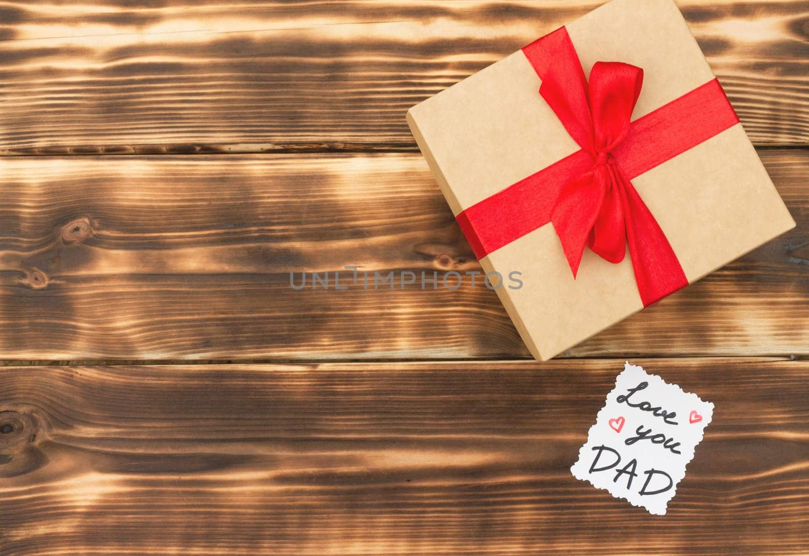 Greeting card Love You Dad with a gift box on a rustic wooden tabletop. Flat lay. Top view. Copy space