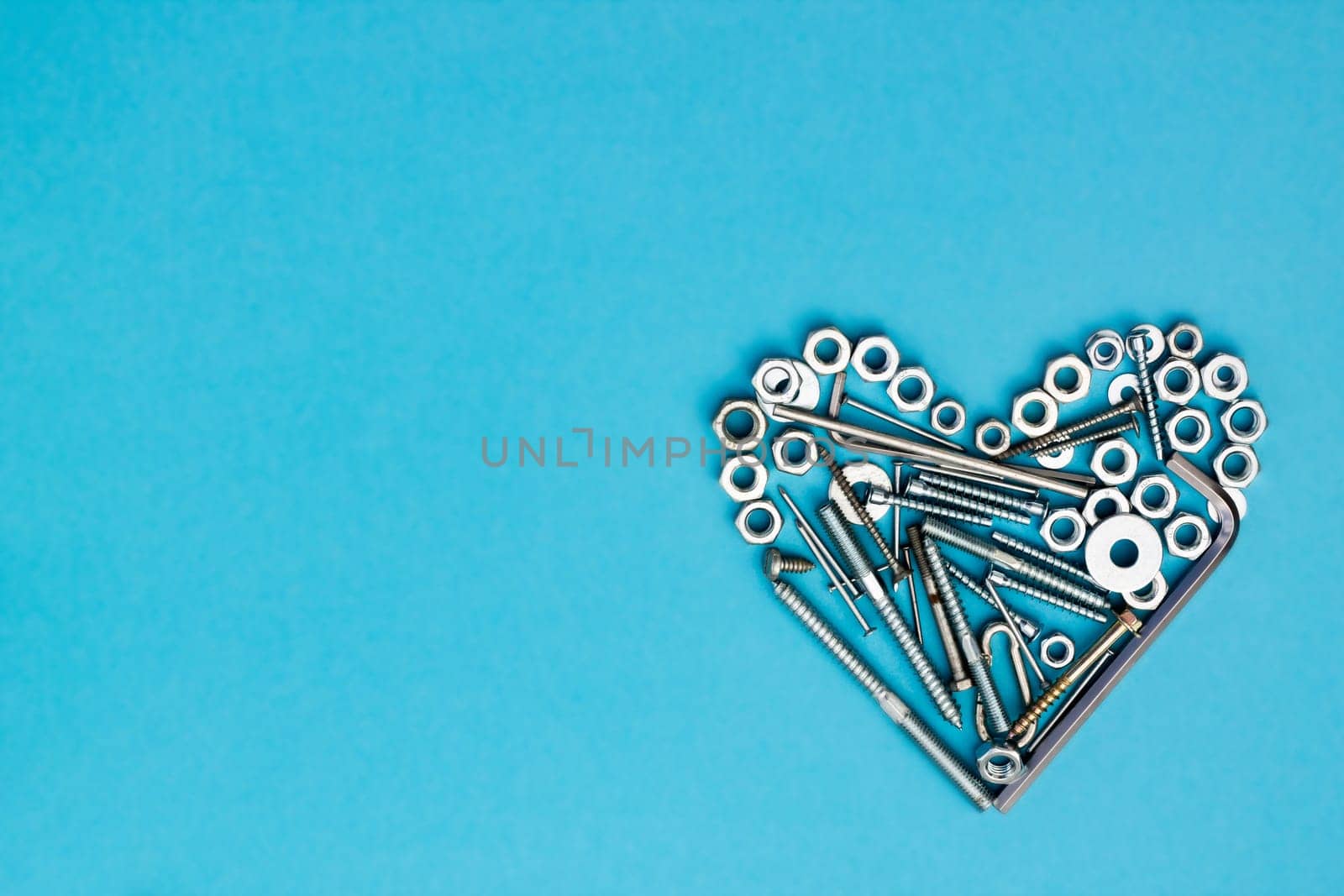 Heart laid out of bolts, nuts, wrenches and other construction tools on a blue background. Father's day concept. Flat lay. Top view. Copyspace