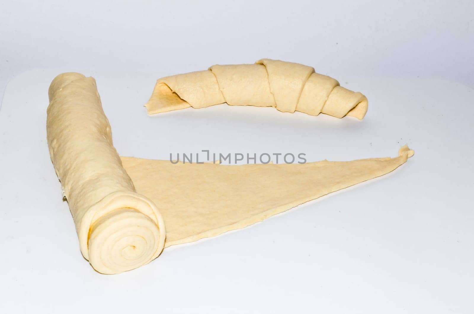 Fresh raw croissant dough on white background