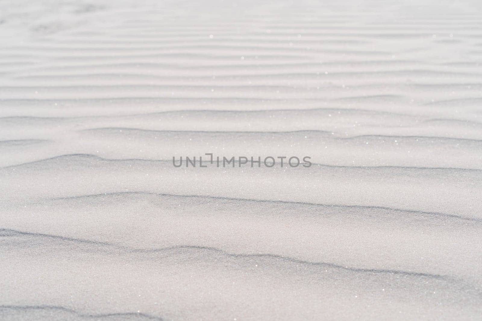 Pattern of sea ripples was left by waves on coastal white sand. Sea coast. Tourism and travel. Calm and serenity. Natural background. Natural texture. Dunes. Abstract drawing.