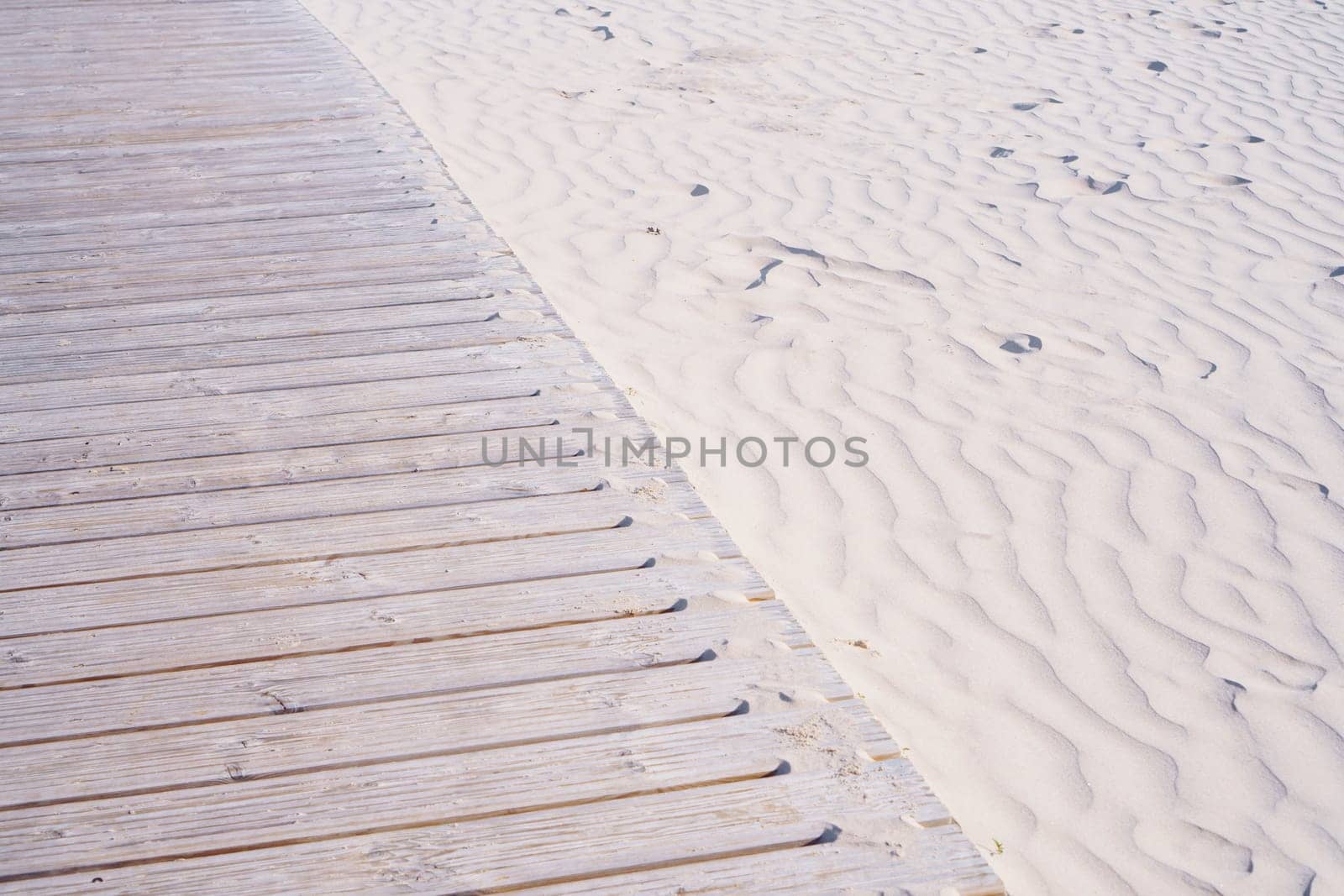 Wooden walkway on beach for walking is located on white sand. Walking along coast in fresh air. Comfort and relaxation. Tourism and travel. Relaxation and meditation. Loneliness and peace.