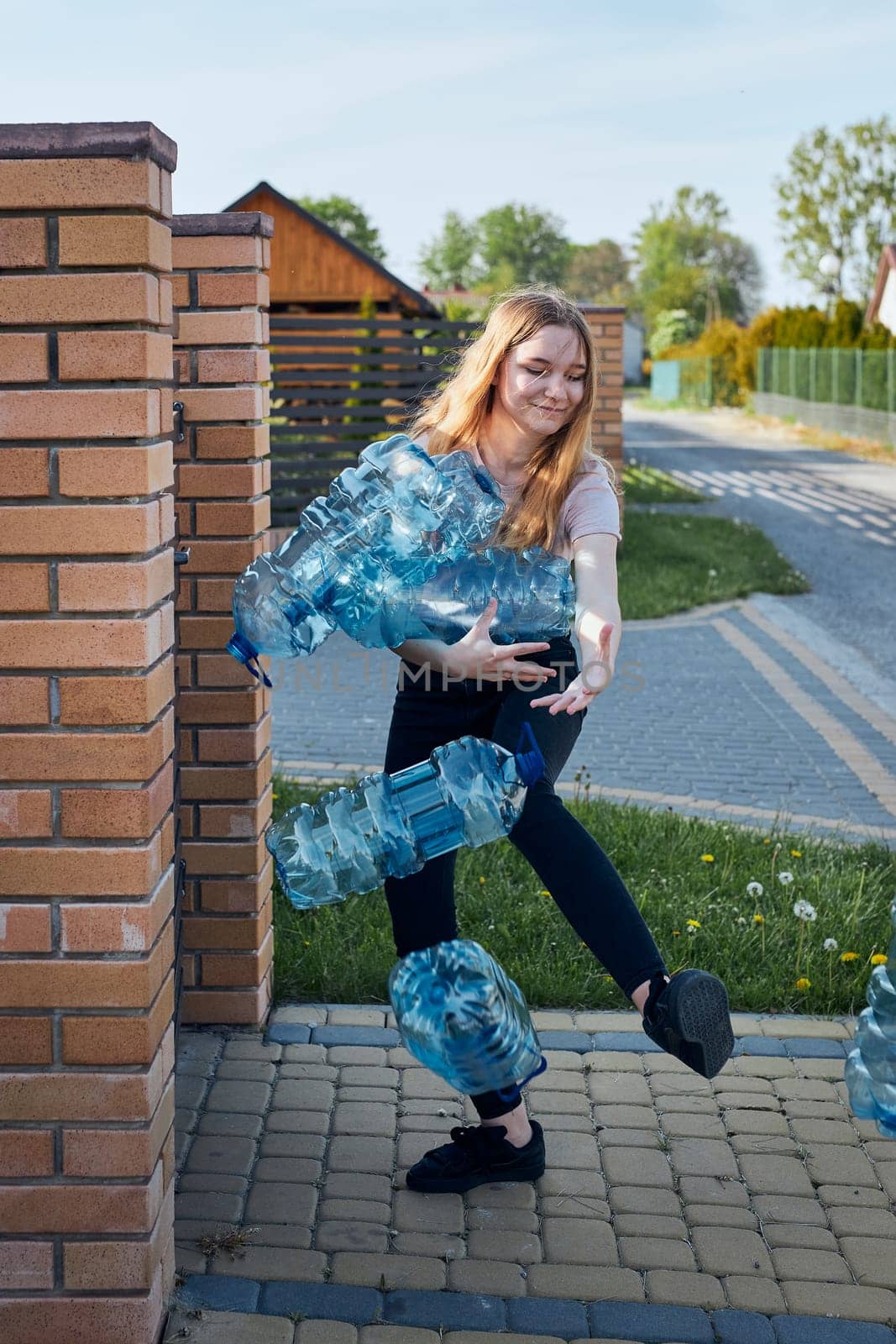 Young woman throwing out empty used plastic water bottles into trash bin. Collecting plastic waste to recycling. Concept of plastic pollution and too many plastic waste. Environmental issue