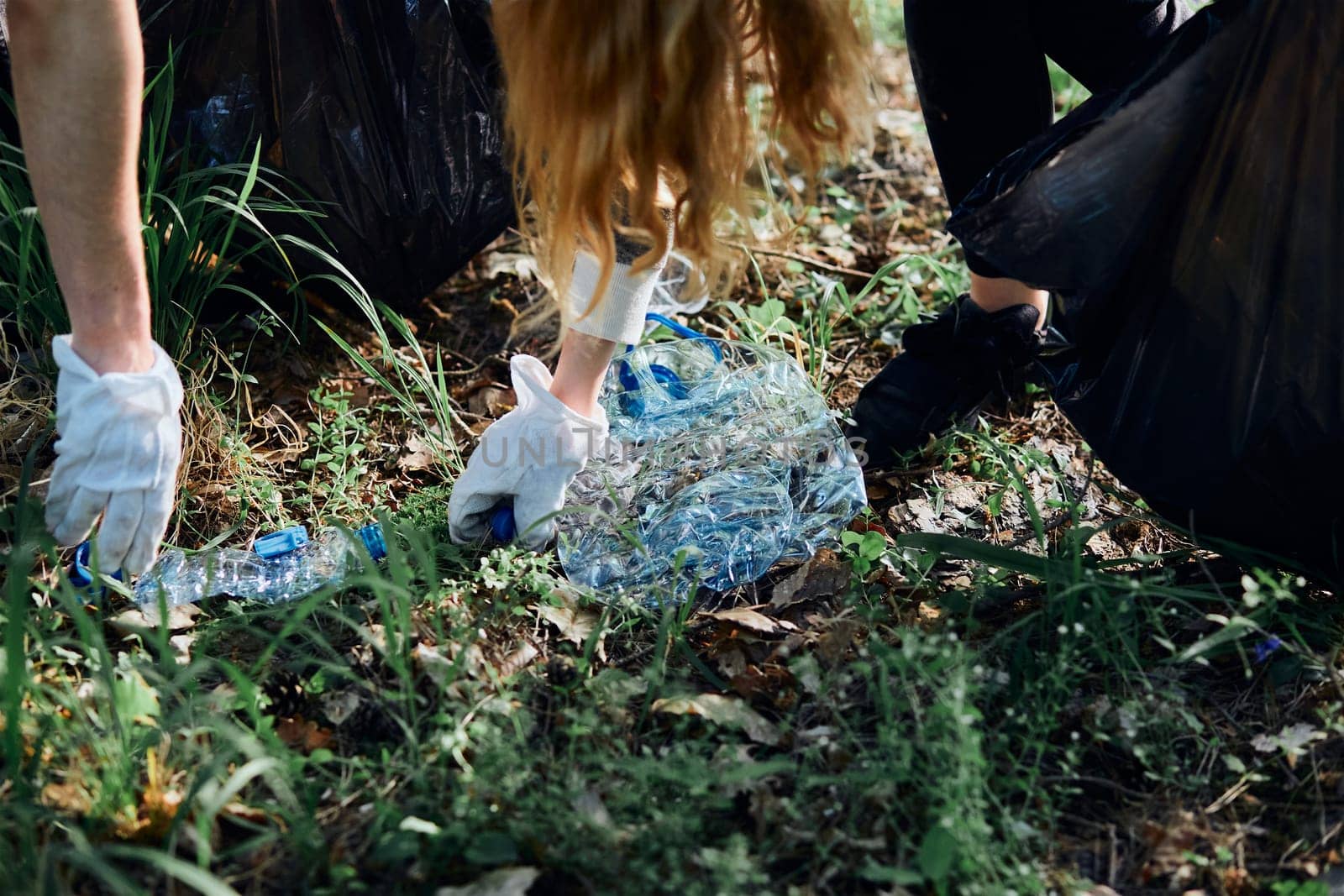 Young man and woman cleaning up a forest. Volunteers picking plastic waste to bags. Concept of plastic pollution and too many plastic waste. Environmental issue. Environmental damage. Responsibility for environment. Real people, authentic situations