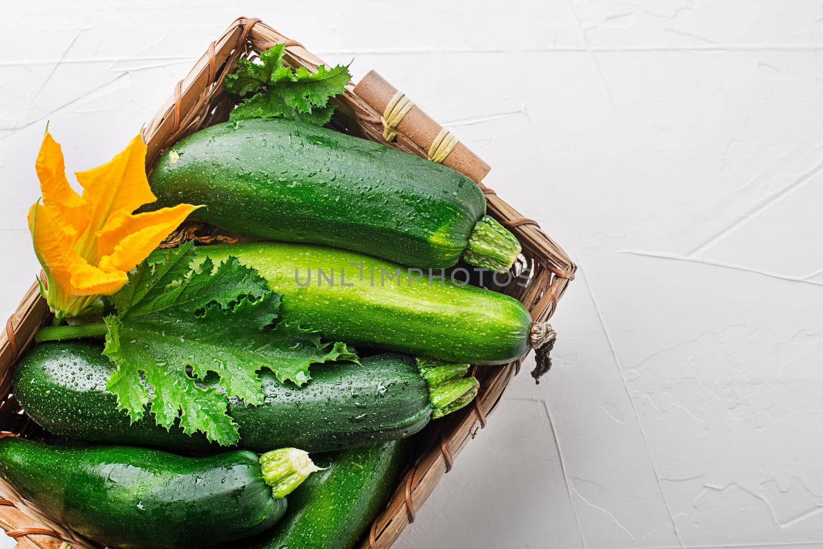 Basket of fresh vegetable crops with fresh zucchini on white background closeup
