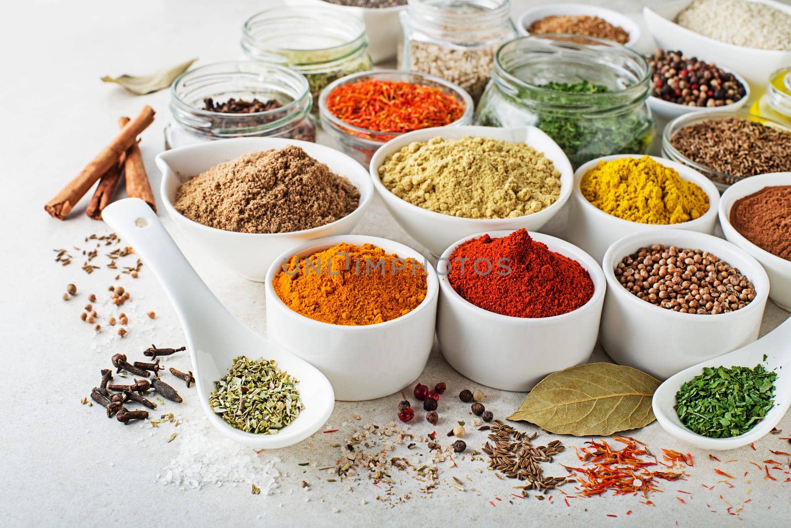 Colorful herbs and spices for cooking meal. Indian and Asian spices On white stone background closeup