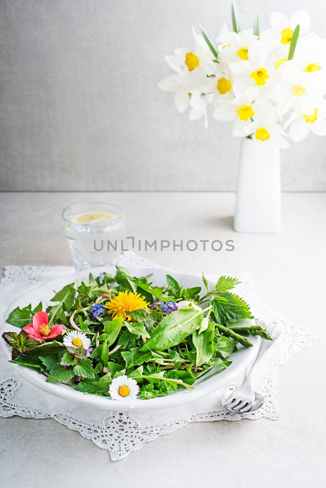 Spring table background with flowers, herbs and plants. Wild garlic, nettle, dandelion and other medicinal herbs and wild edible plants growing in early spring.