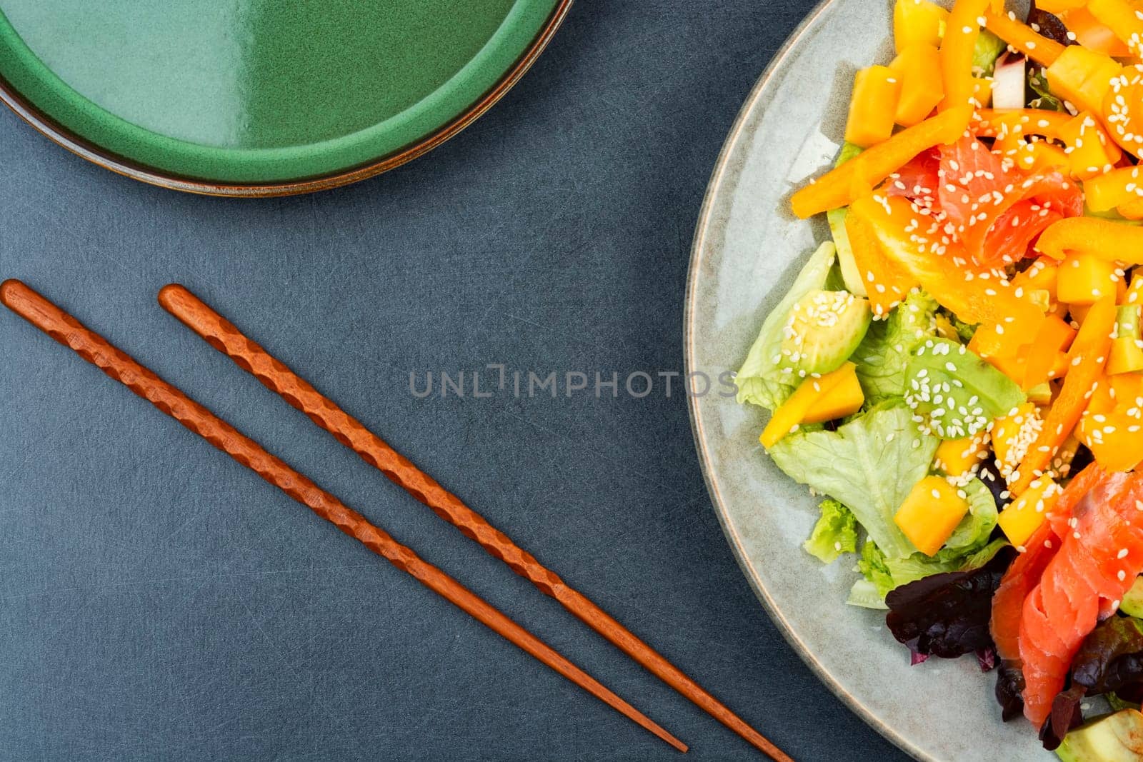 Asian salad with salted salmon, mango, sesame and vegetables.Salad and chopsticks. Space for text