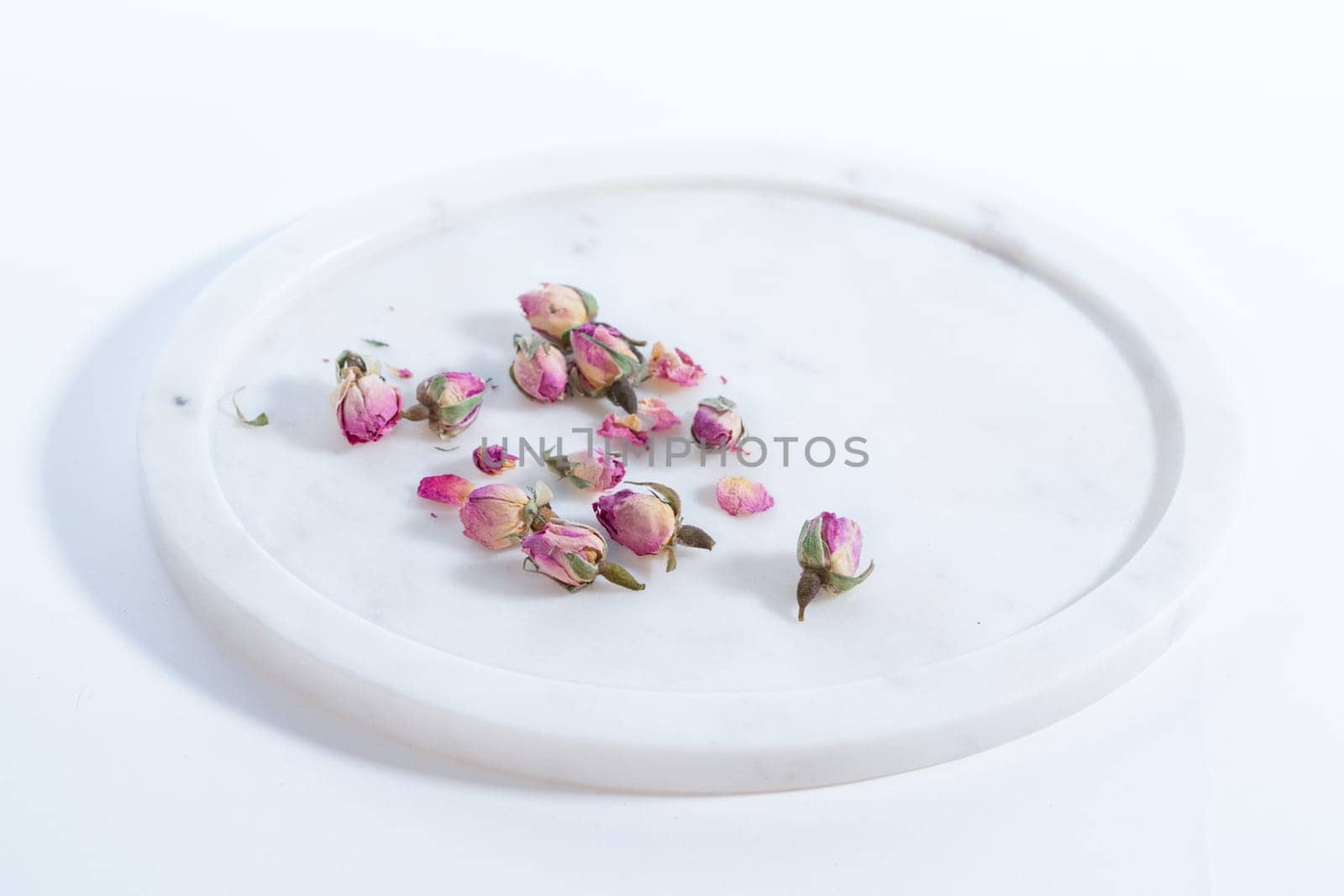 beautiful and pink small dried roses on a on a marble plate white background