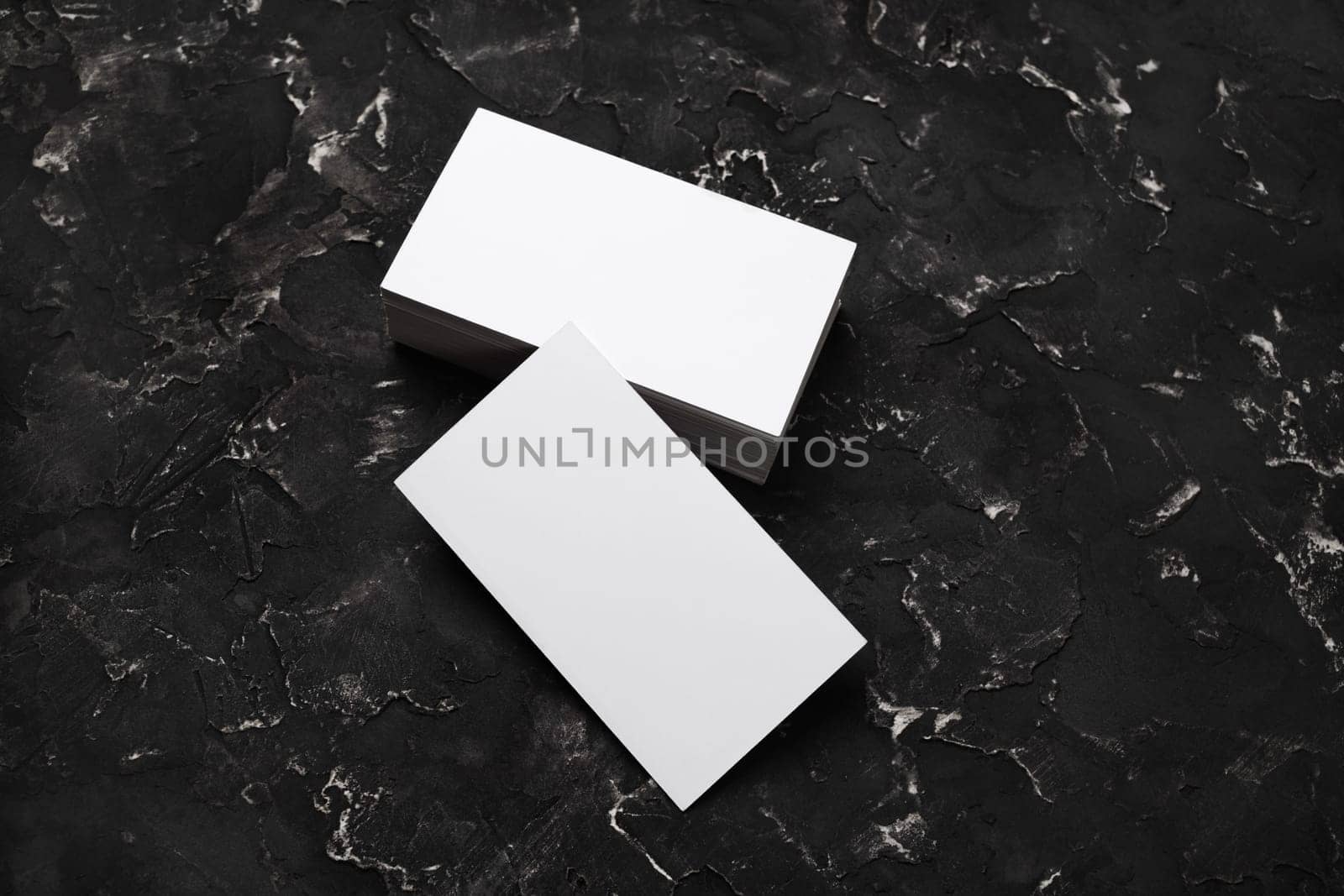 Photo of blank business cards on black plaster background. Mock-up for branding identity. Studio shot.