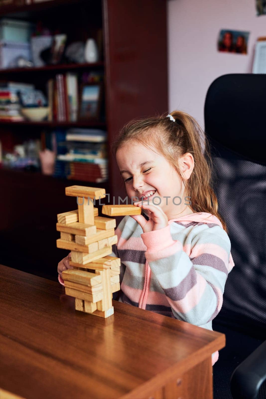 Little girl preschooler playing with wooden blocks toy building a tower. Concept of building a house