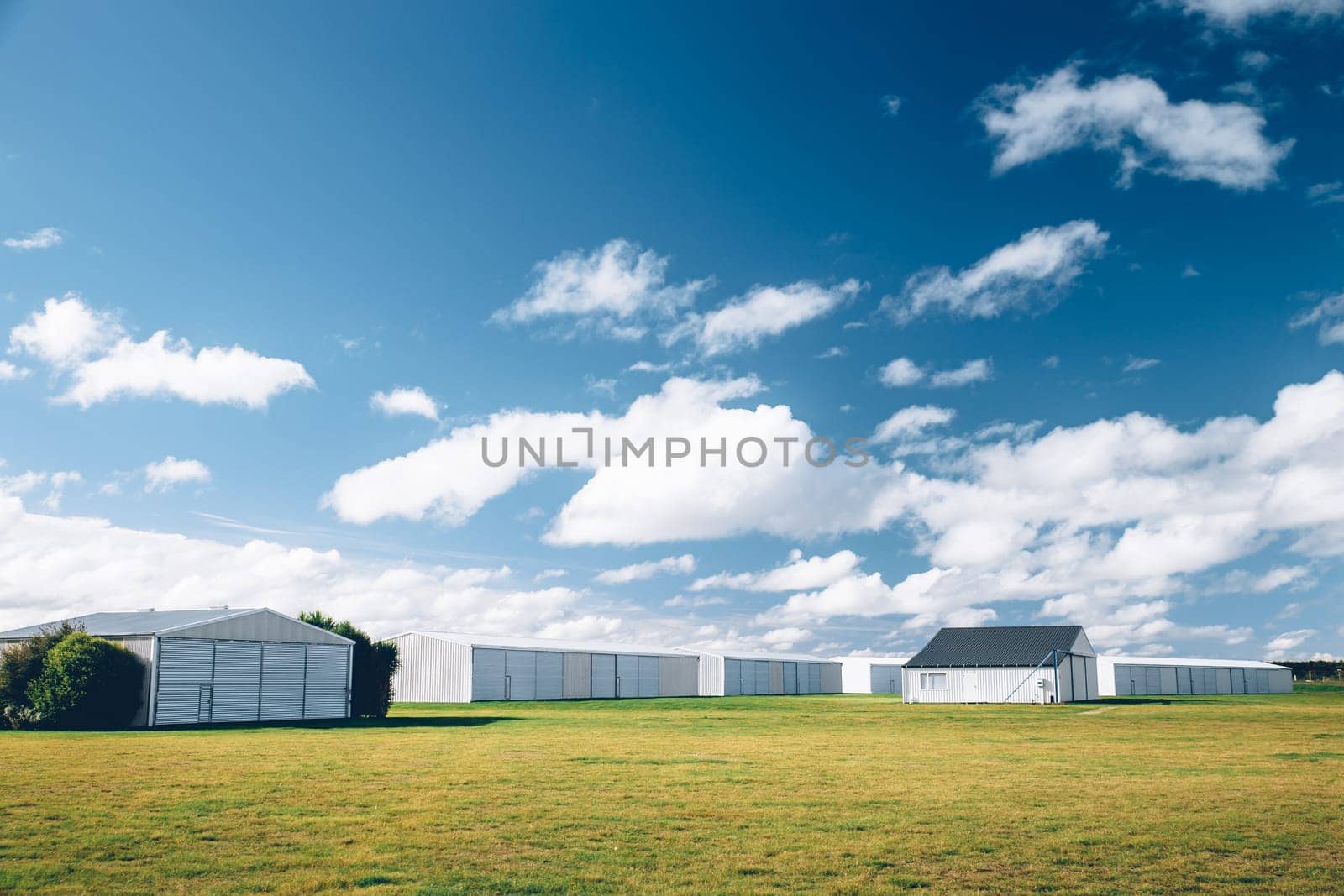 Steel barn on a farm with cloudy blue sky.