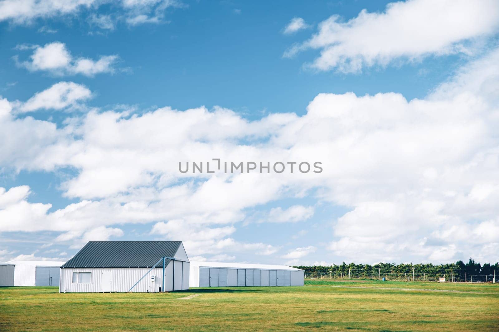 Steel barn on a farm with cloudy blue sky.