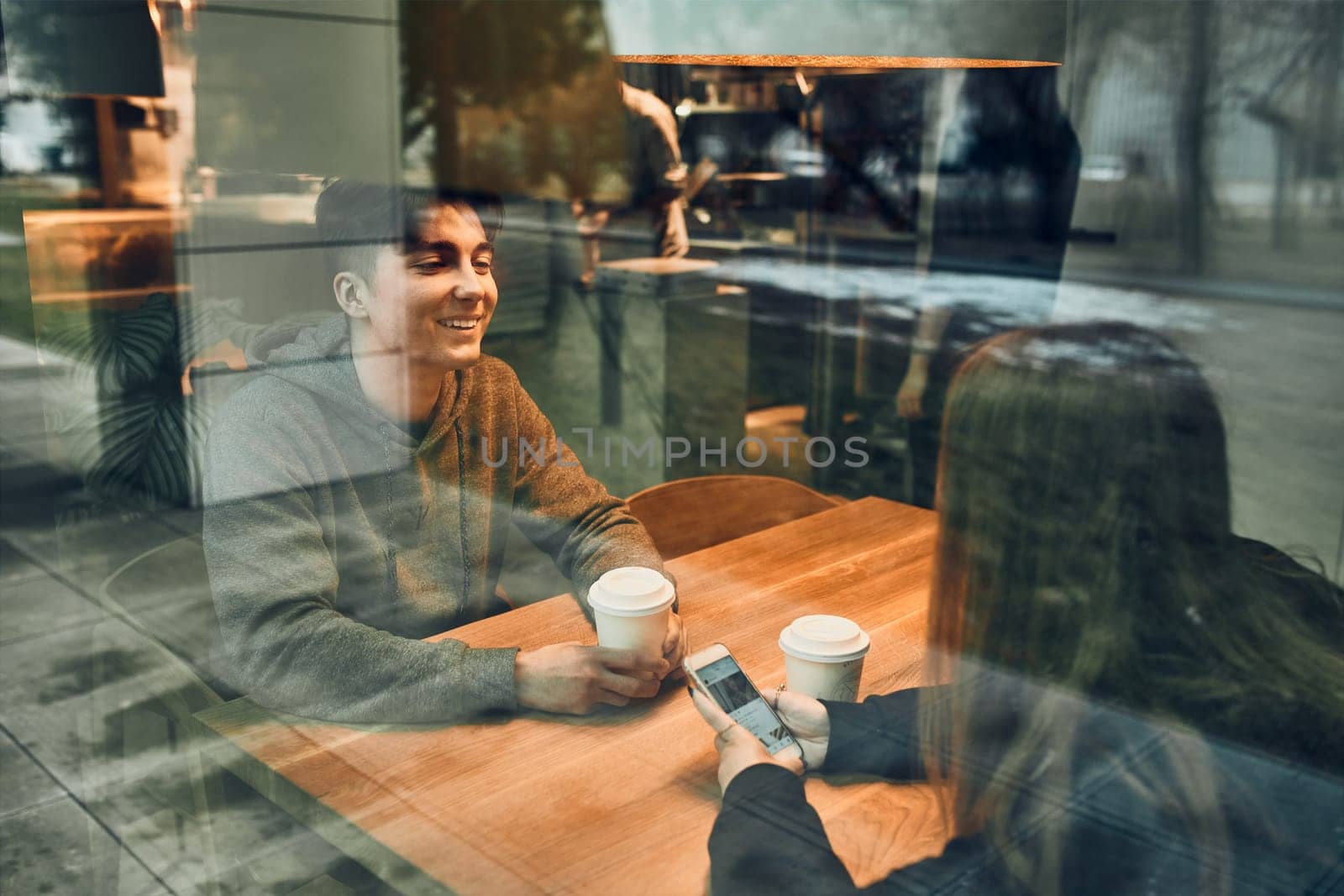 Friends having a chat, talking together, drinking coffee, sitting in a cafe. Young man and woman relaxing in cafe, having a break