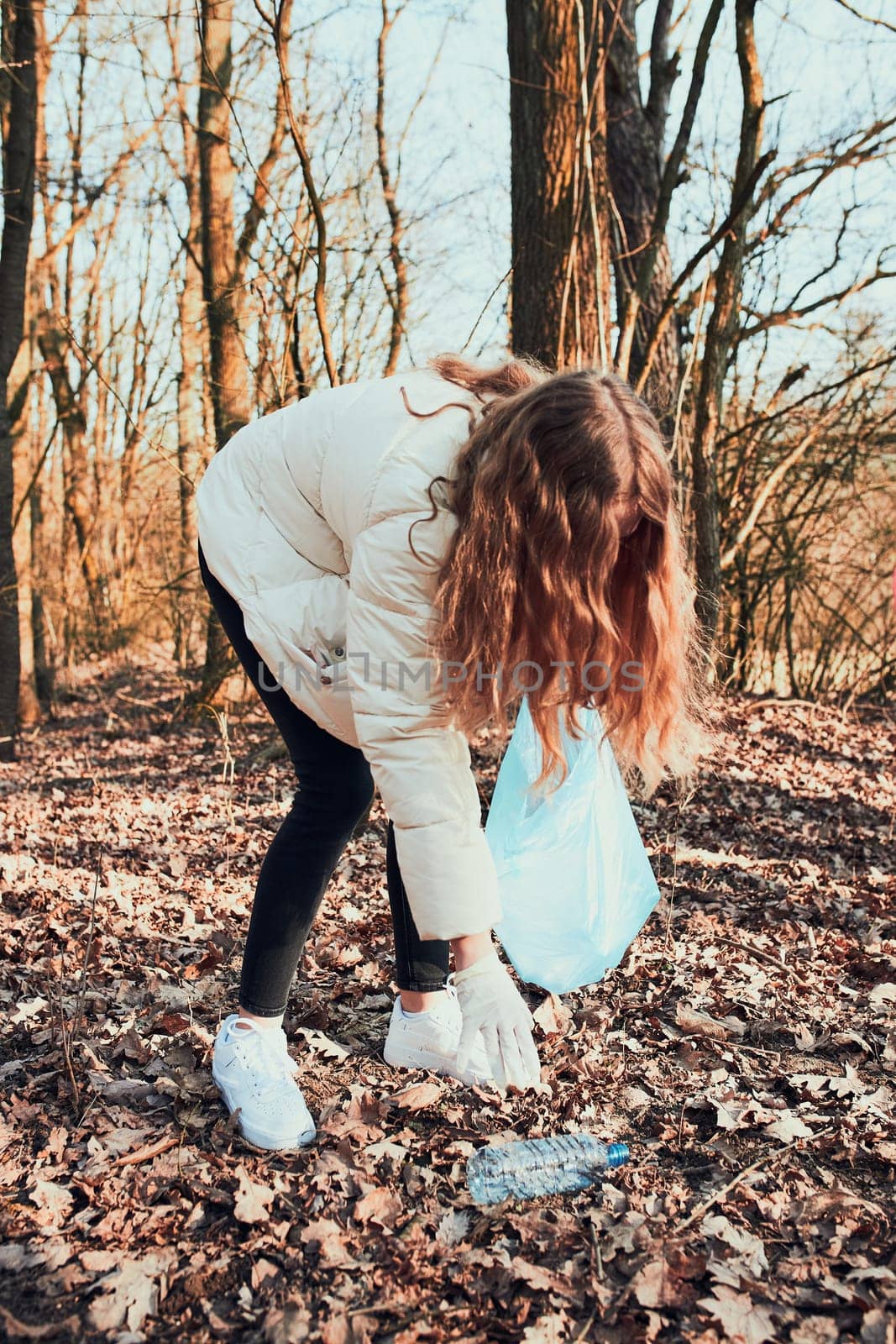 Young woman cleaning up a forest. Volunteer picking plastic waste to bags. Concept of plastic pollution and too many plastic waste. Environmental issue. Environmental damage. Responsibilitiy for environment. Real people, authentic situations