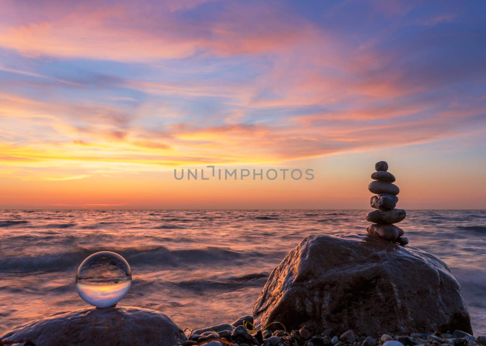 Stone pyramids and glass sphere on the dreamy Baltic Sea sand beach on Rügen for the spectacular sunset
